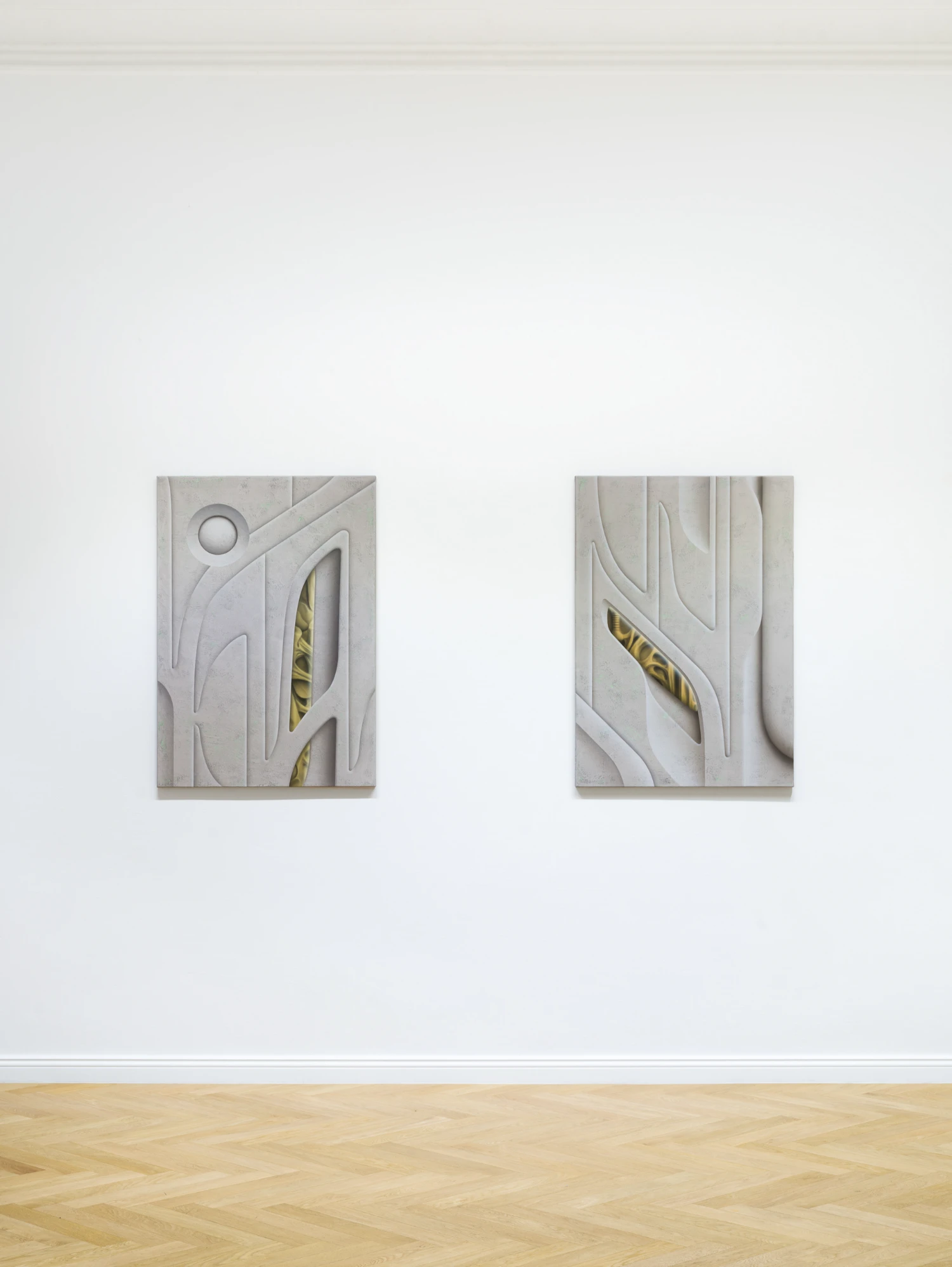 Bloom by Tomáš Absolon Milan Vagač at SPOT Gallery — Two carved plaster relief panels mounted on a white gallery wall, each roughly 60 × 45 centimeters, positioned symmetrically in the frame.