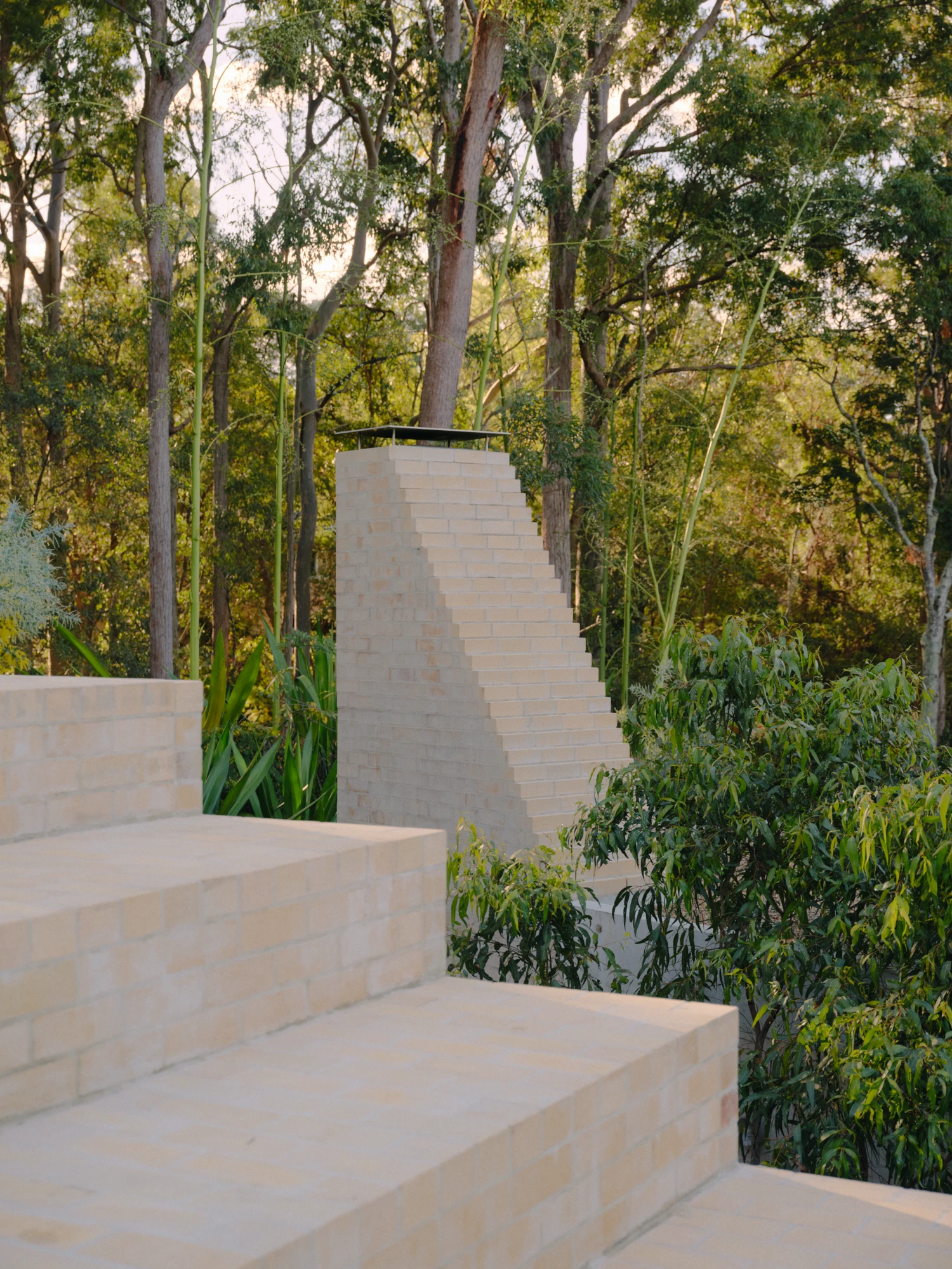 Stuartholme House by Nielsen Jenkins + Michael Lumby — Stepped concrete planters and retaining walls create a monumental ascending geometry through dense eucalyptus forest.