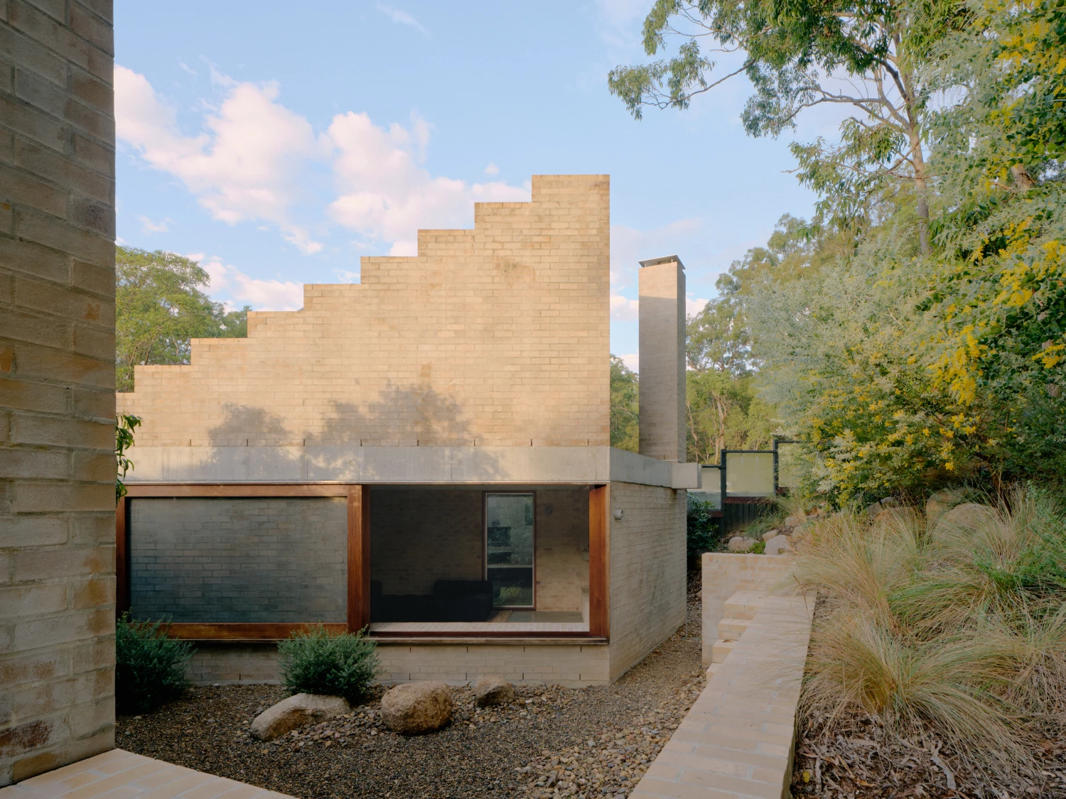 Stuartholme House by Nielsen Jenkins + Michael Lumby — The stepped brick facade ascending the full wall height dominates the composition, its geometric progression creating a monumental backdrop to the modest...