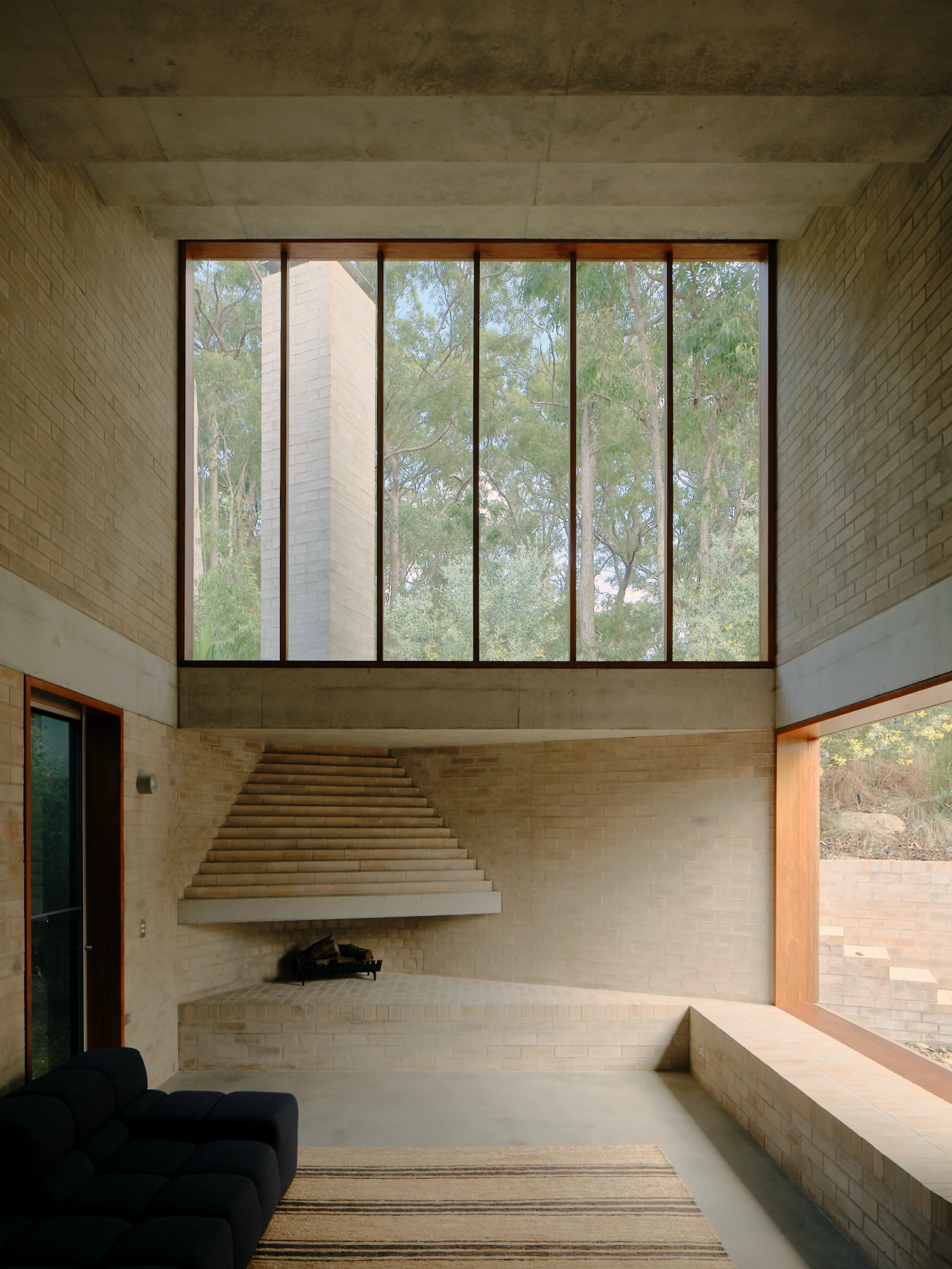 Stuartholme House by Nielsen Jenkins + Michael Lumby — A sunken interior space anchors the composition, its recessed floor plane establishing spatial recession toward the landscaped gully beyond.