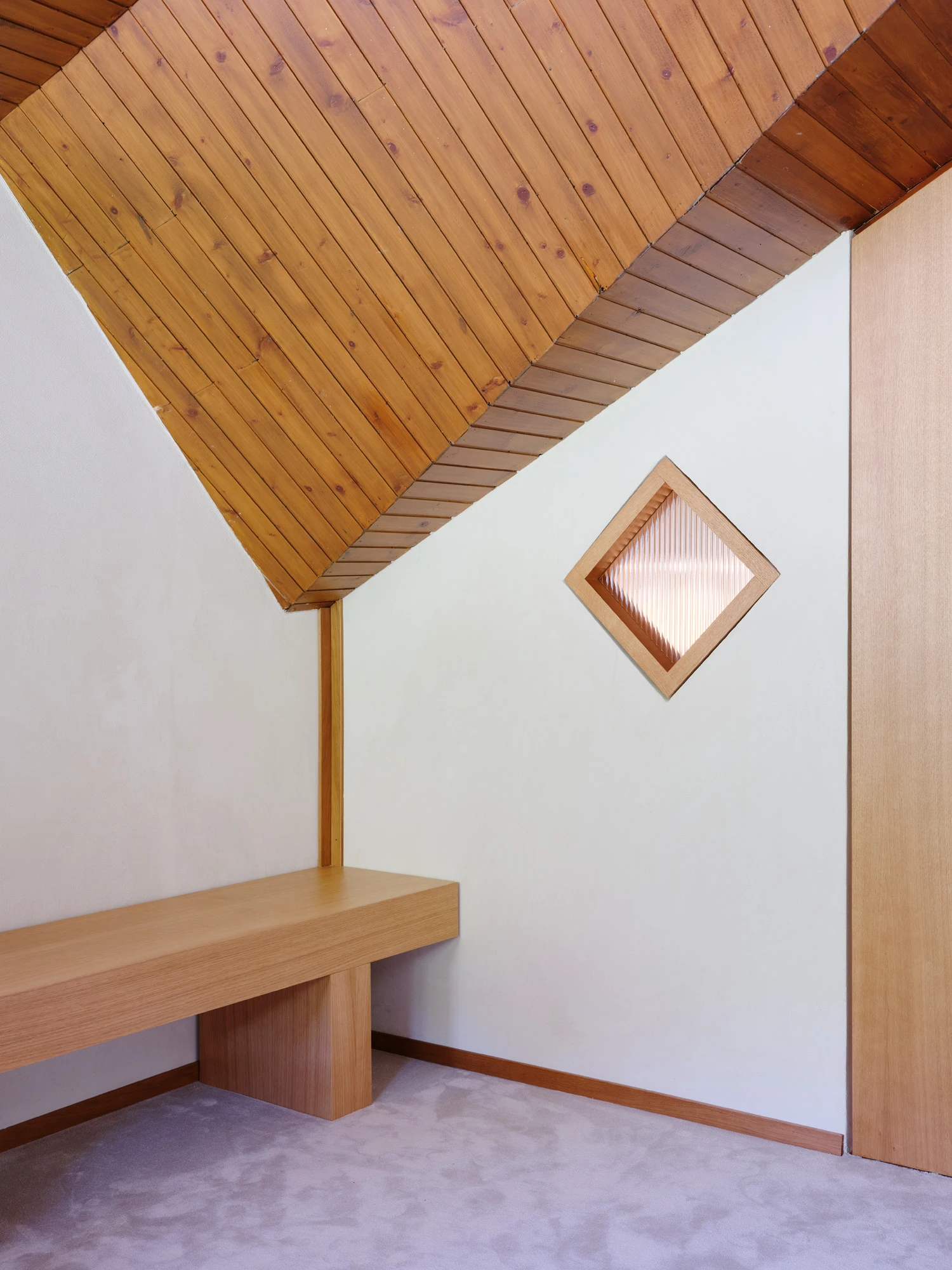 An Interior at Giomein by co.arch — A timber-lined interior demonstrates structural honesty through exposed roof geometry.