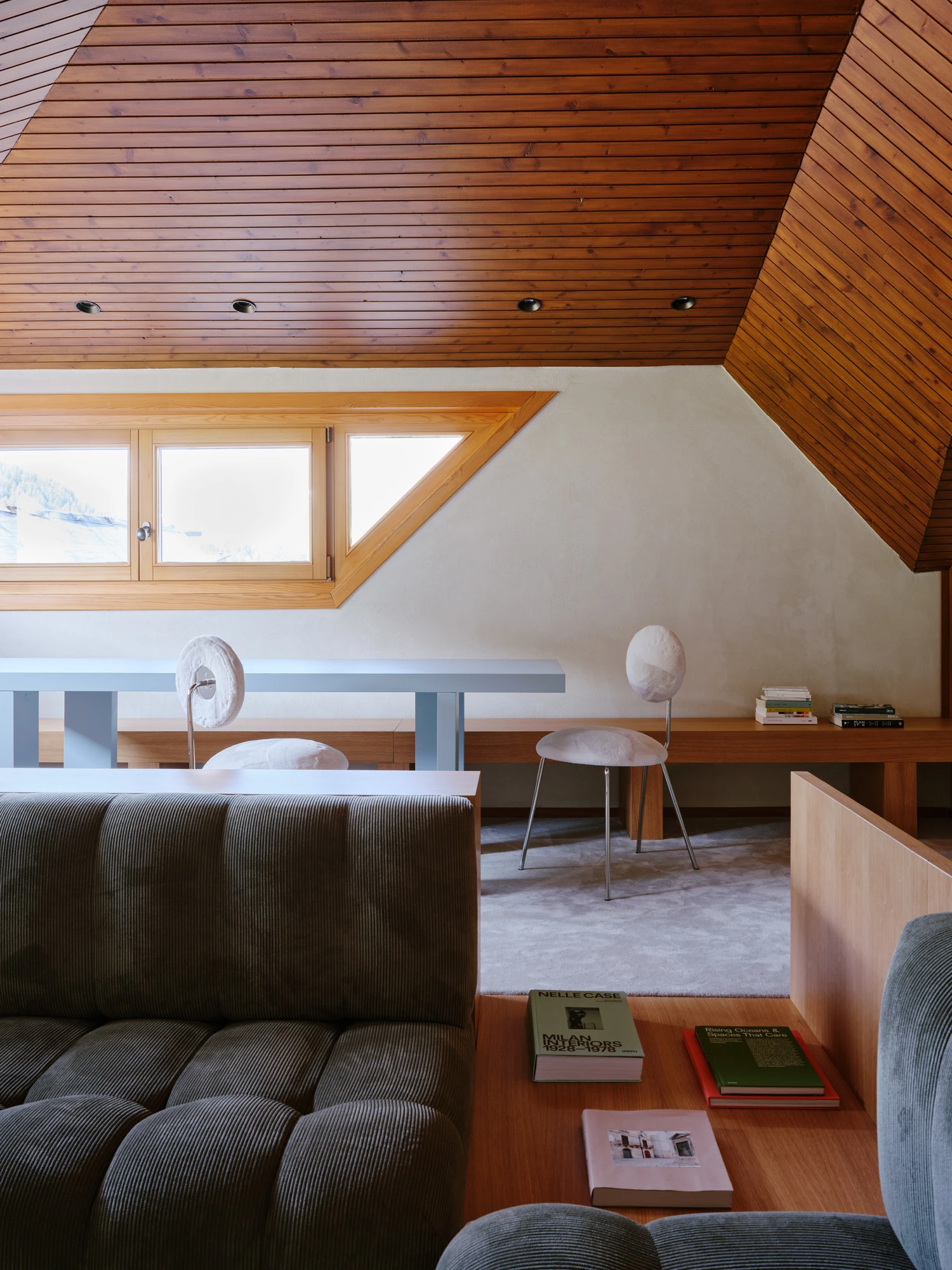 An Interior at Giomein by co.arch — A pitched-roof attic interior in timber showcases the structural logic of the Alpine chalet's geometry.