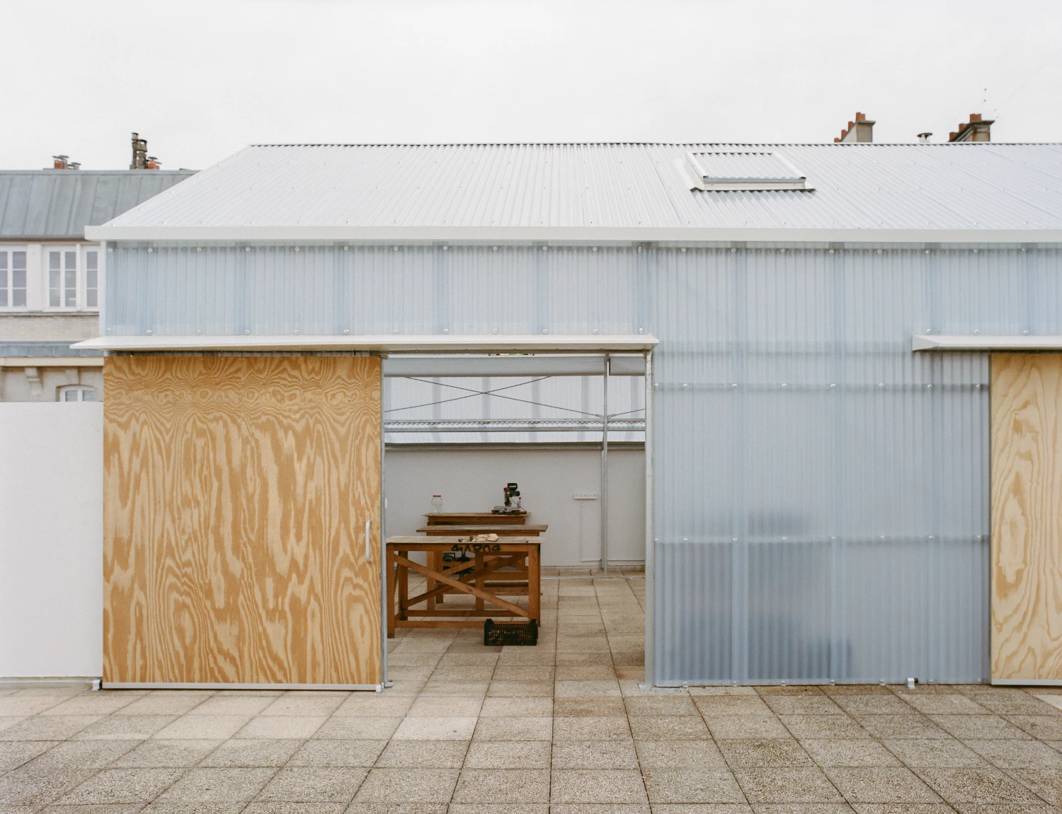 Rooftop Educational Farm by rerum architectes — A transparent polycarbonate greenhouse interior reveals a working cultivation space on a Parisian rooftop.