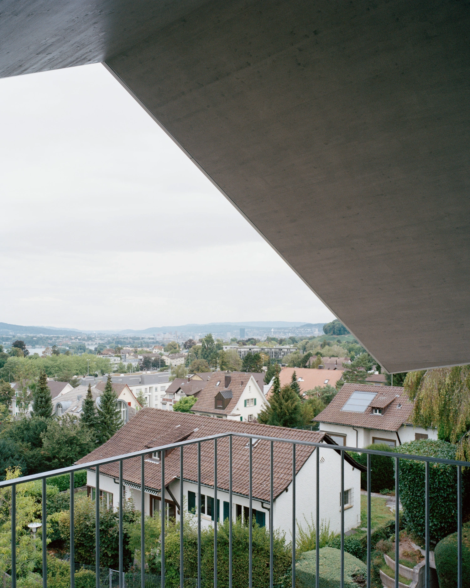 House on a Slope by KARAMUK KUO — Viewed from an elevated terrace, the house's deep southern cantilever creates a dramatic shadow line across the monolithic concrete soffit.