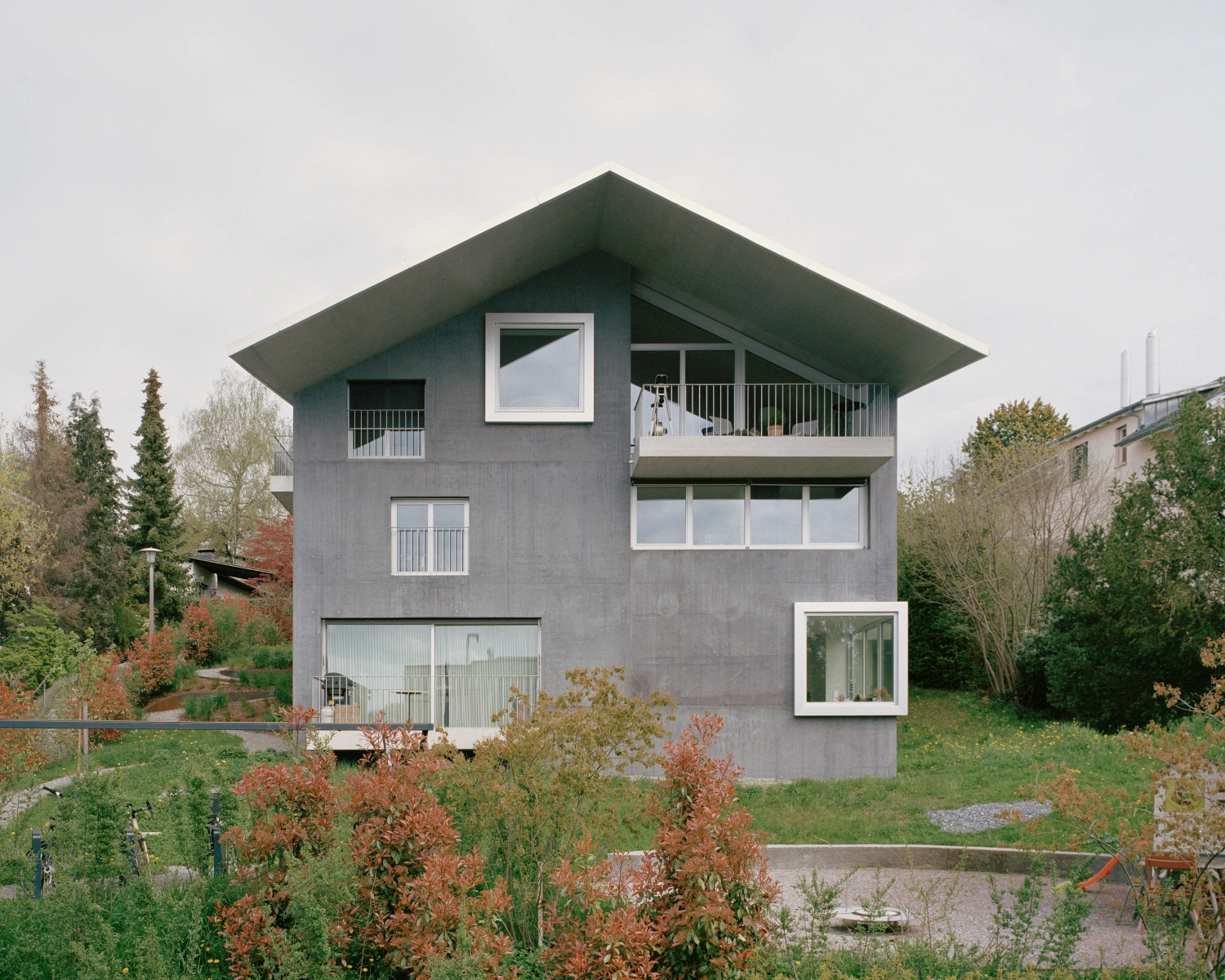 House on a Slope by KARAMUK KUO — A three-story concrete residence in Zollikon presents a deceptively simple facade that conceals five distinct dwelling types.