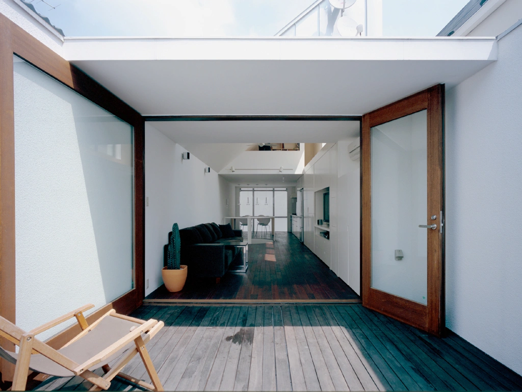 Long Tall House by Spacespace — Interior view through large operable glass panels reveals the depth of Long Tall House's five-storey vertical sequence.