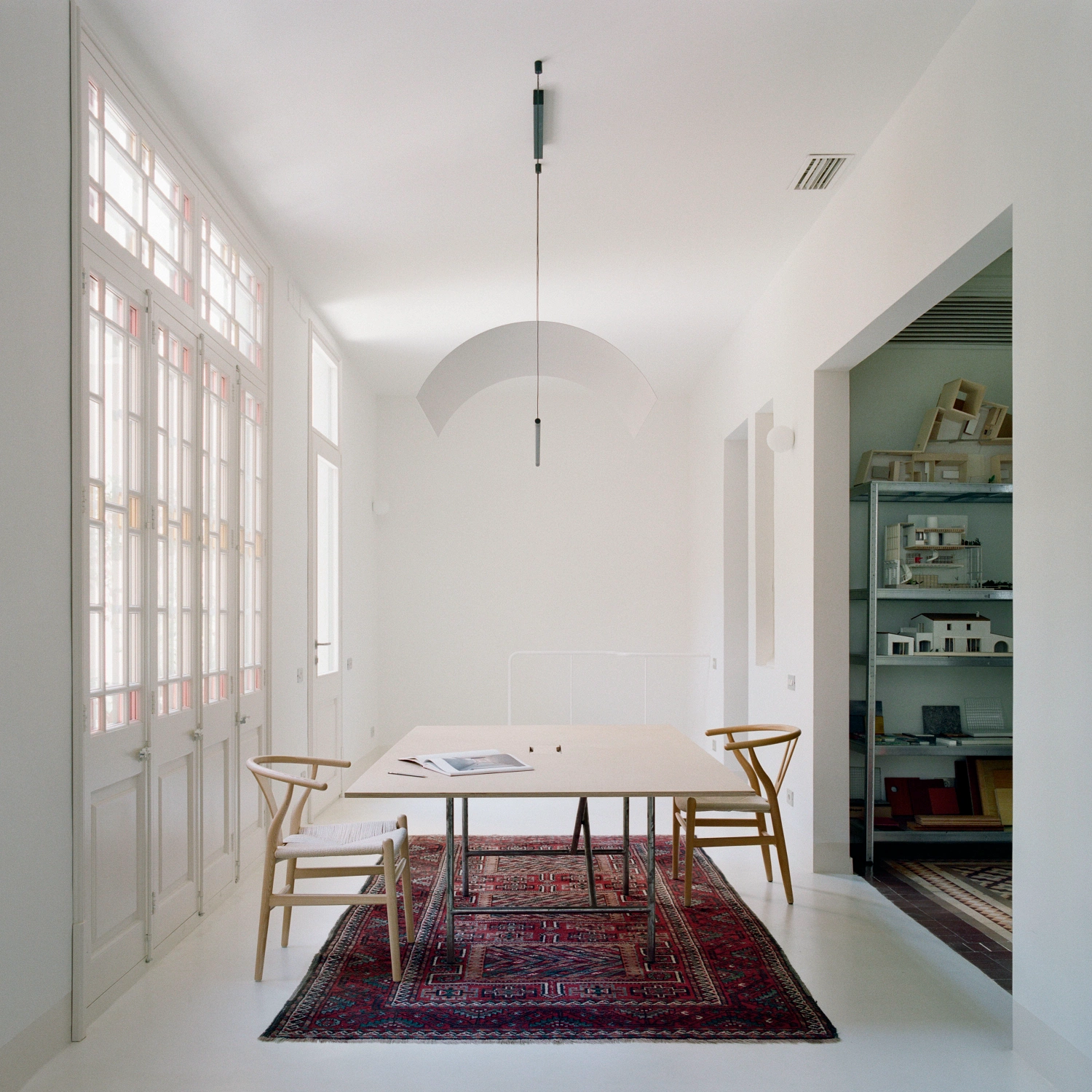 LL731 by Aramé Studio — A dining space unified by a curved plaster vault that suspends above a timber table, anchored on a red and navy geometric patterned rug.