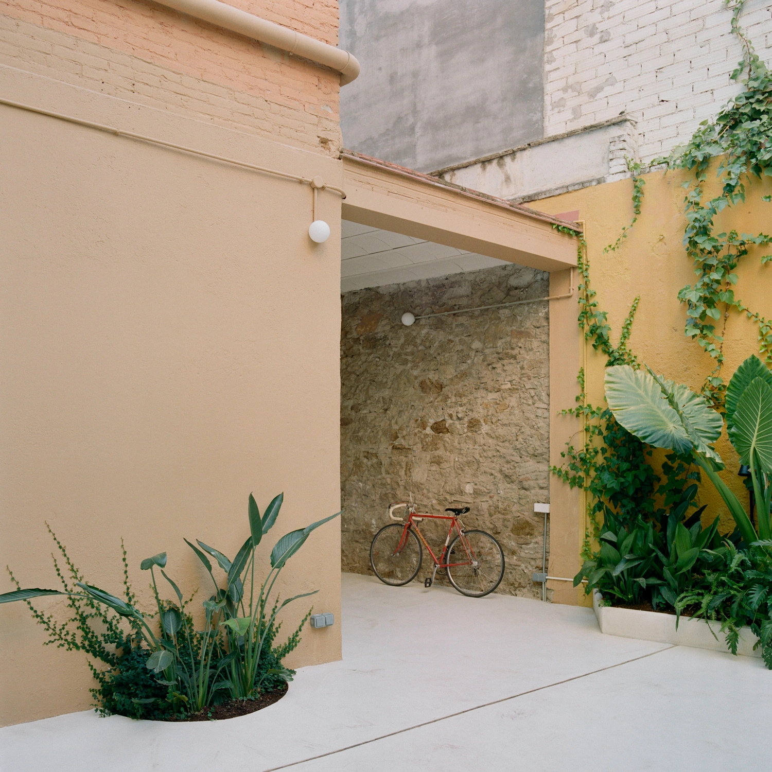 LL731 by Aramé Studio — A threshold space frames the project's spatial strategy: the peach-rendered entrance wall opens onto a passage where a red road bicycle leans against...
