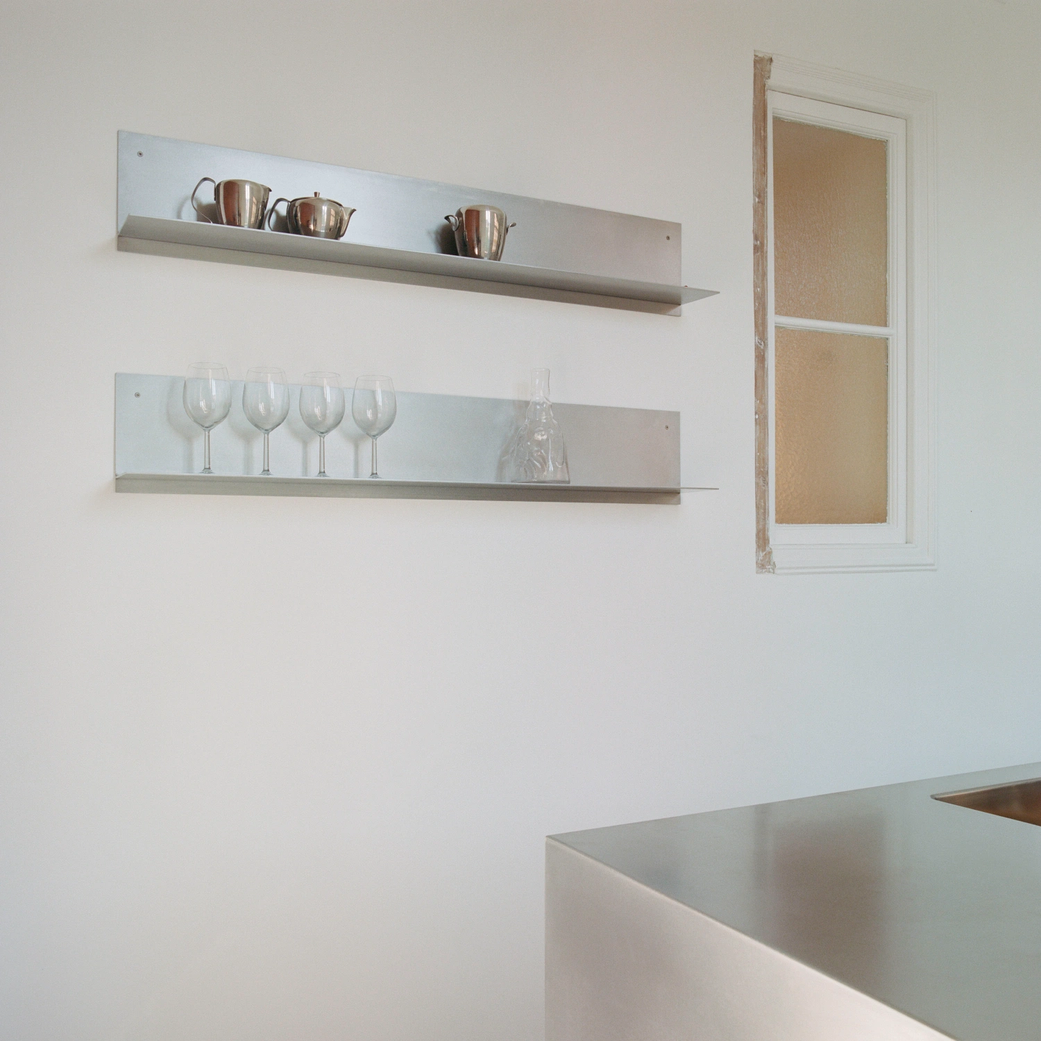 LL731 by Aramé Studio — Wall-mounted display shelving in a Barcelona kitchen renovation demonstrates restrained materiality and functional clarity.