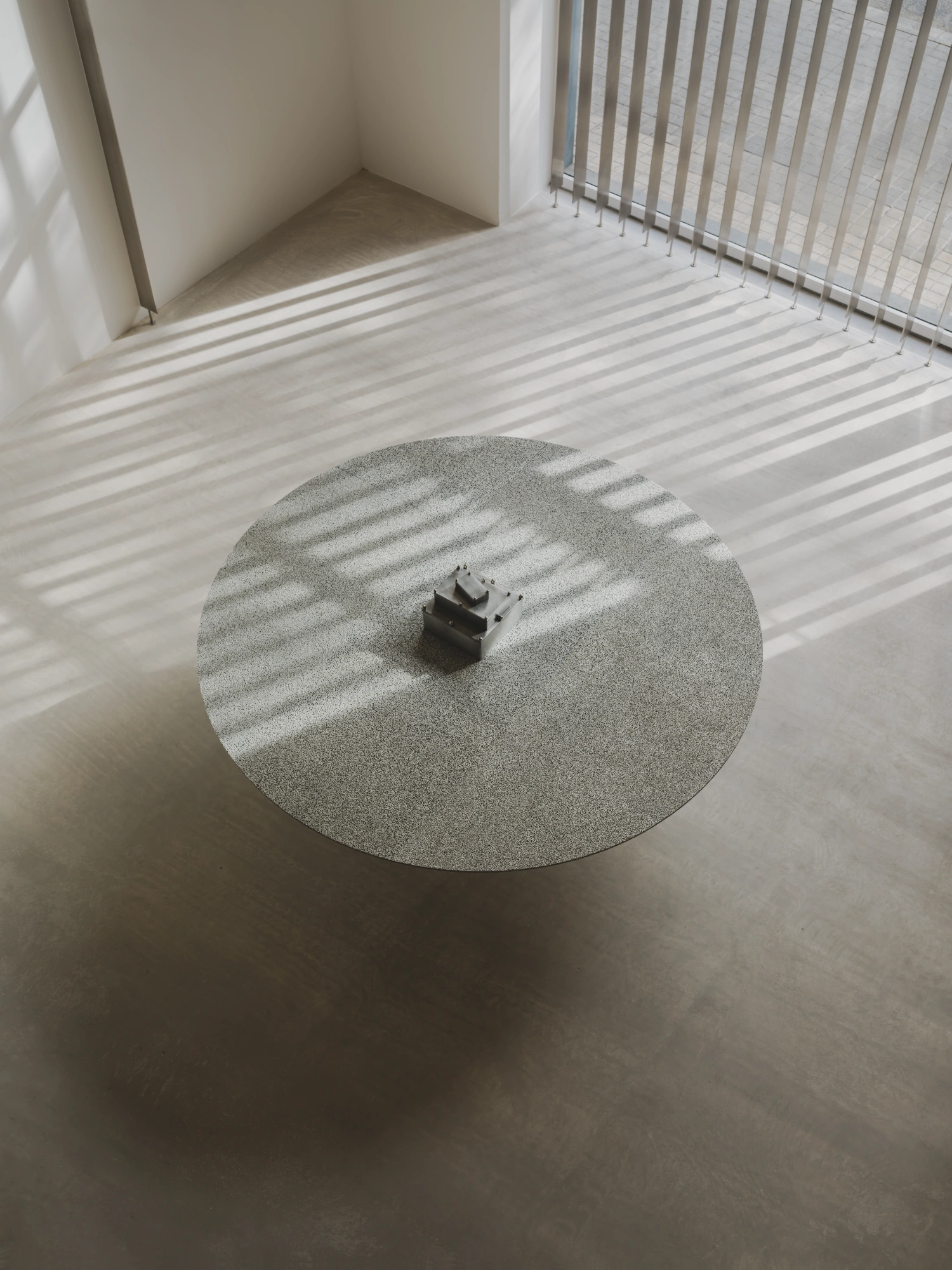 M.I.G. Store by AVOIR — Overhead view of a circular concrete pedestal table positioned centrally on polished concrete flooring.