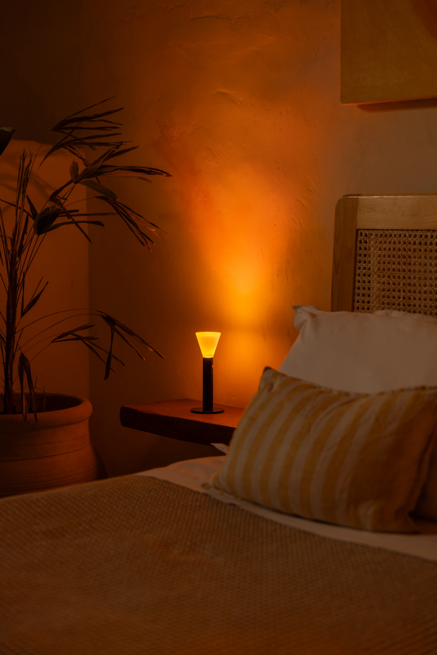 Halo Mag (Flame + Bloom) designed by Mandalaki — Halo Mag's Flame edition positioned on a wooden nightstand within a bedroom setting, its translucent satin-finish diffuser emitting warm yellow light...