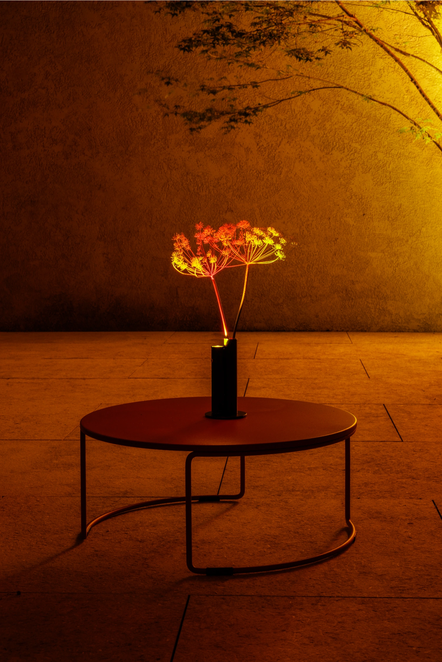 Halo Mag (Flame + Bloom) designed by Mandalaki — Mandalaki's Halo Mag (Flame) positioned on a circular rust-toned table with splayed metal legs.