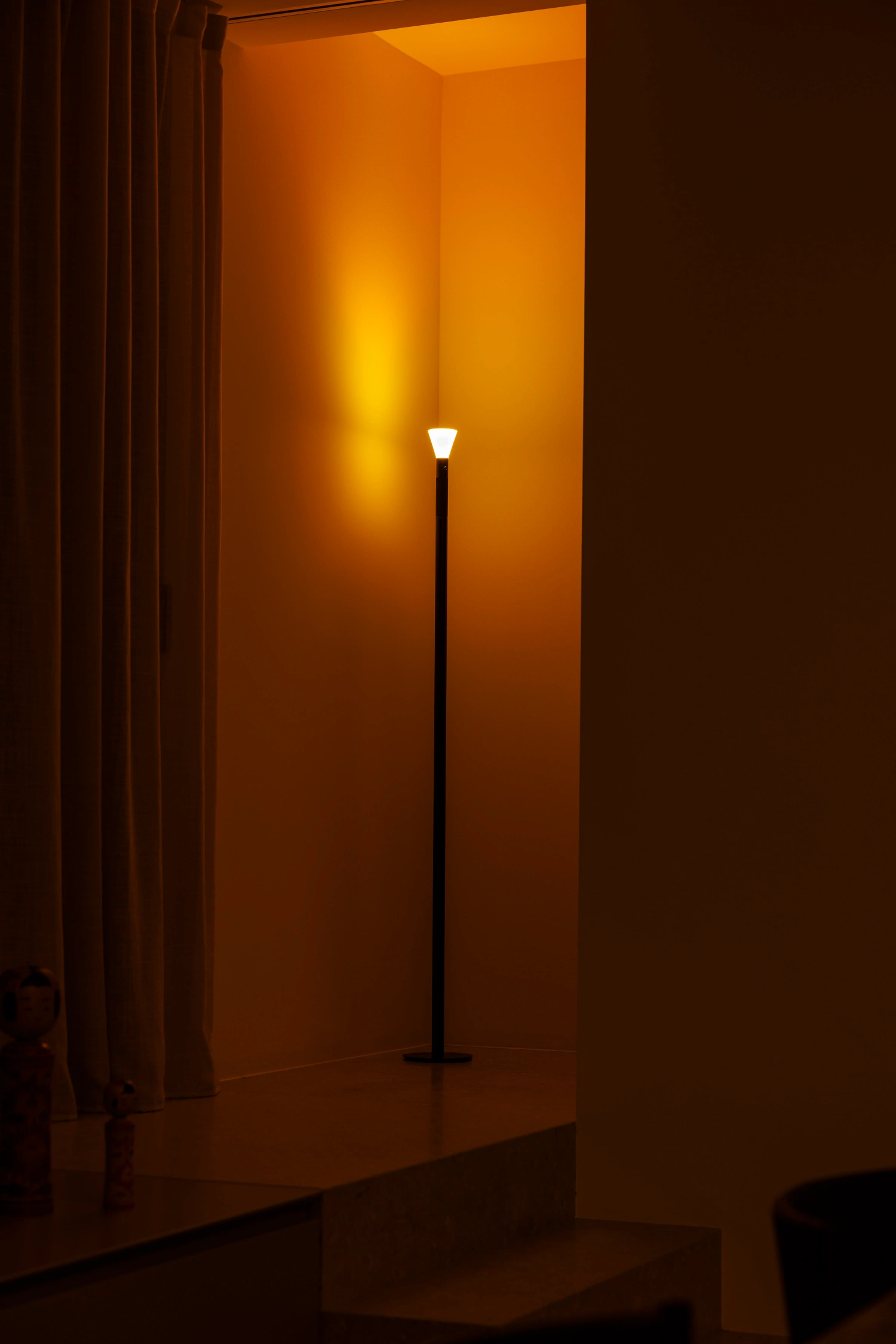 Halo Mag (Flame + Bloom) designed by Mandalaki — A floor-standing lamp from Mandalaki's Halo series produces warm yellow light diffusing through a translucent satin-finish diffuser, casting a golden glow...