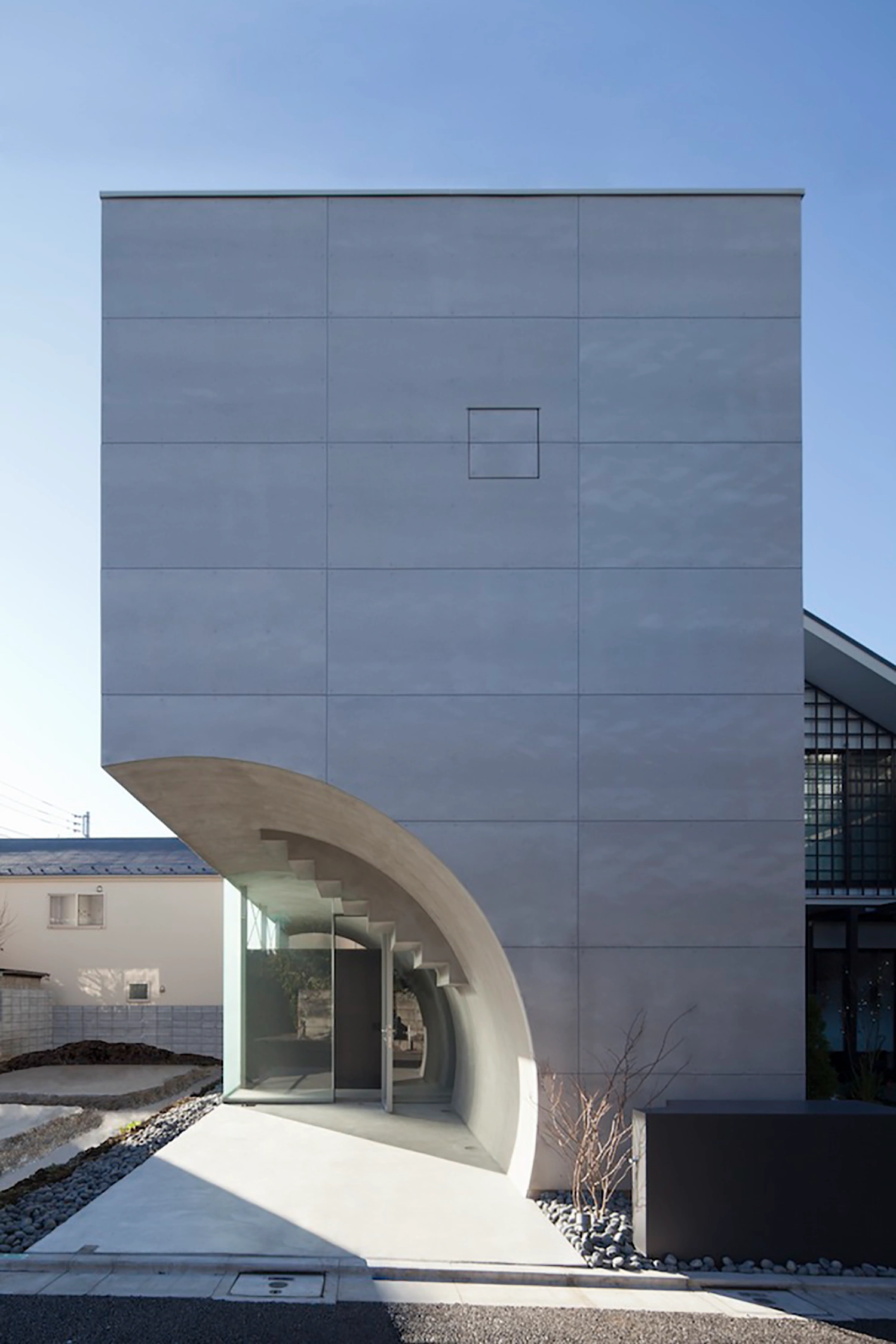 Tunnel House by Makiko Tsukada Architects — The entrance portal of Tunnel House presents a dramatic sectional cut through the building's monolithic form.