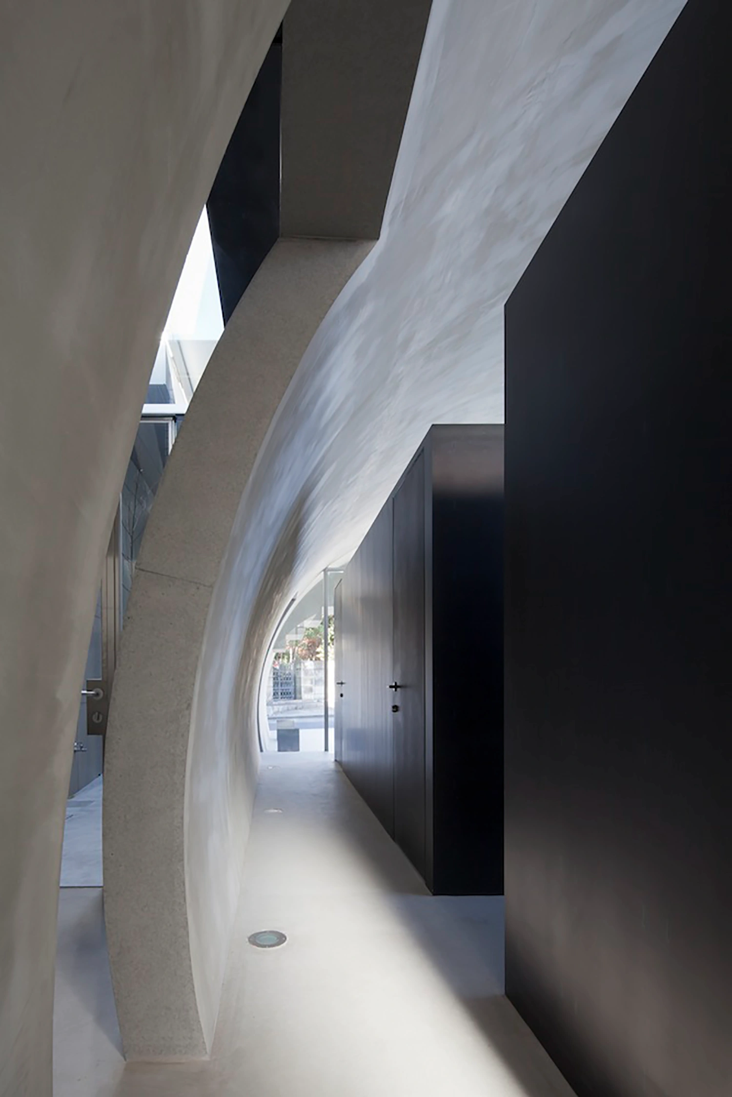 Tunnel House by Makiko Tsukada Architects — A luminous passage carved through the Tunnel House reveals the quarter-cylinder void that defines the project's primary architectural gesture.