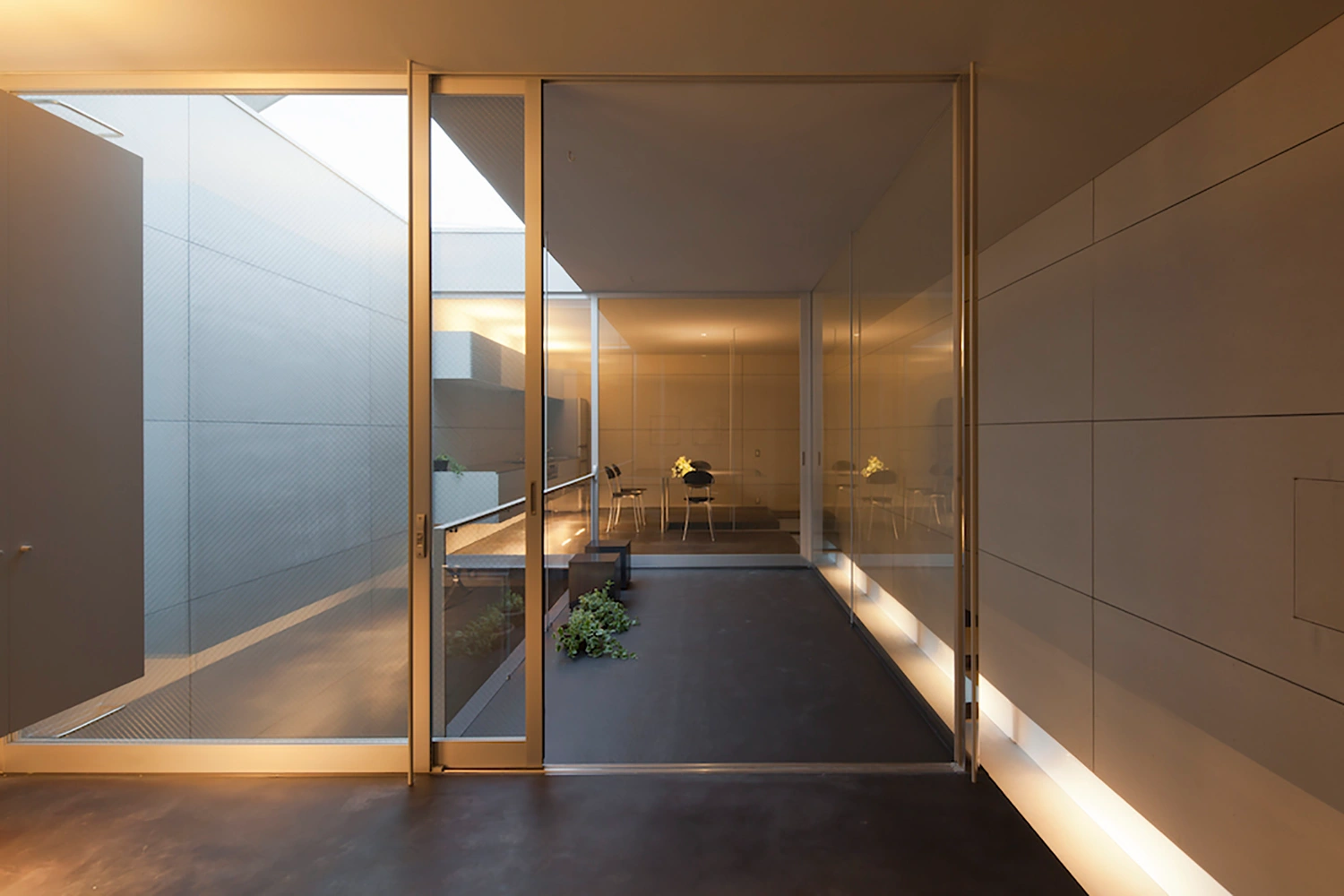Tunnel House by Makiko Tsukada Architects — The luminous tunnel entrance frames the threshold between street and interior, its curved white concrete walls creating a quarter-cylinder void that...