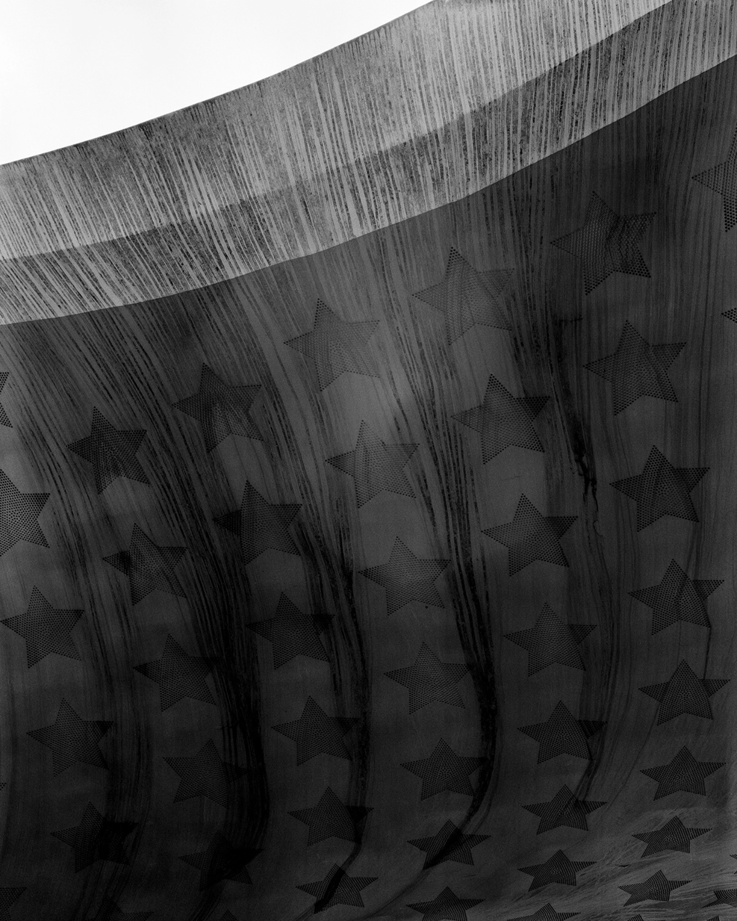 The Internal Crusade by Zexuan Zeng — A black-and-white photograph of sheer fabric with densely printed star motifs arranged in vertical columns.