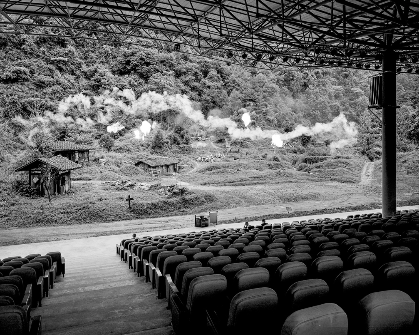 The Internal Crusade by Zexuan Zeng — A drive-in theatre's empty seating rows of black rubber tires face a distant rural valley, creating an inverted perspective on leisure and ideology.