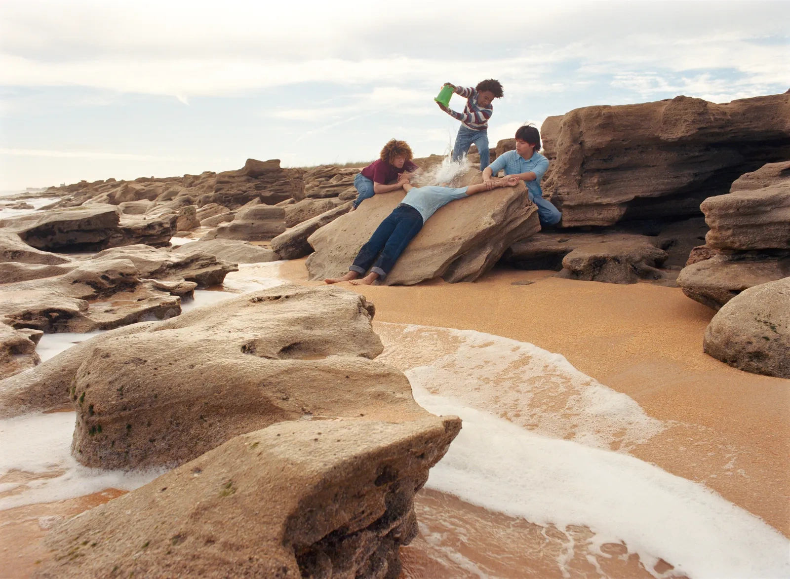 Florida Boys by Josh Aronson — Four figures occupy a rocky beach scattered with sandstone outcroppings and tidal pools.
