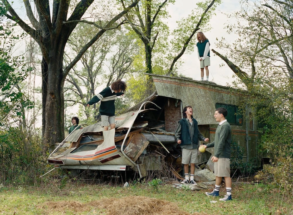 Florida Boys by Josh Aronson — A young person suspended mid-swing from a gnarled tree branch, body weight distributed through extended arms, creates a focal point against the canopy.