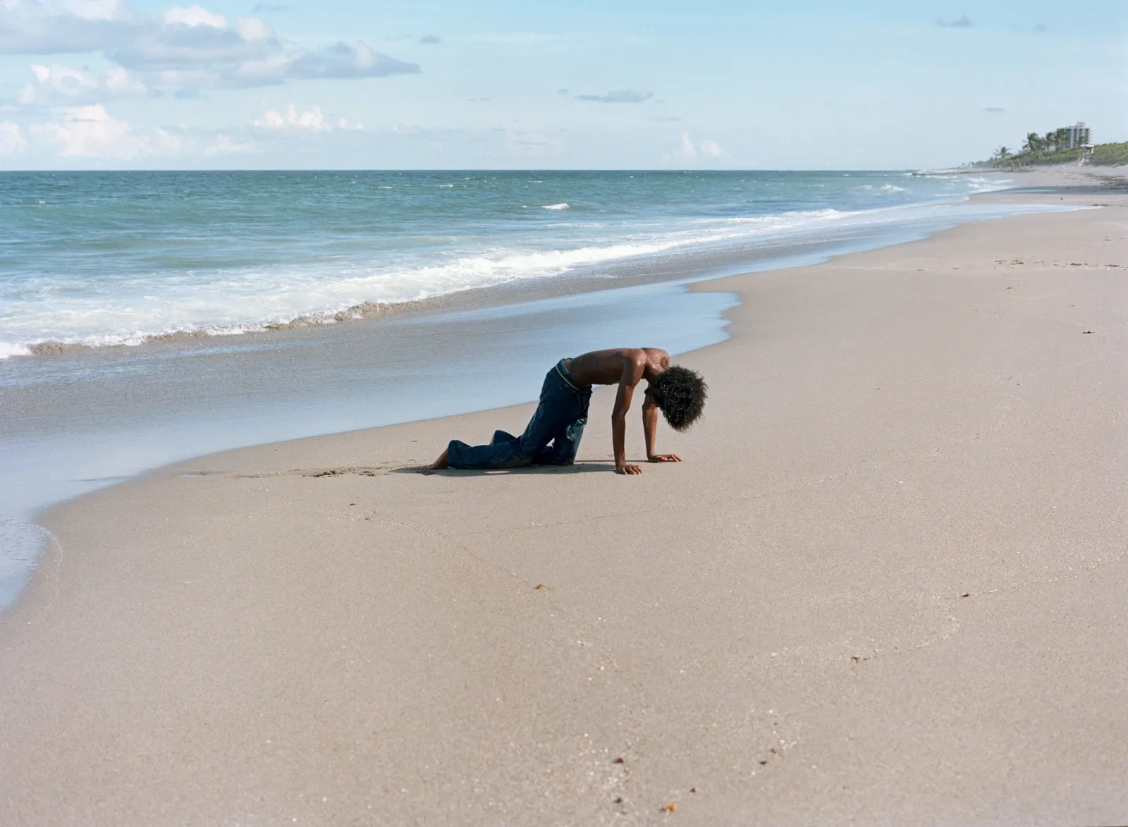 Florida Boys by Josh Aronson — A shirtless man performs a deep backbend on wet sand at the waterline, his body arched in an inverted pose with hands planted firmly in the beach.