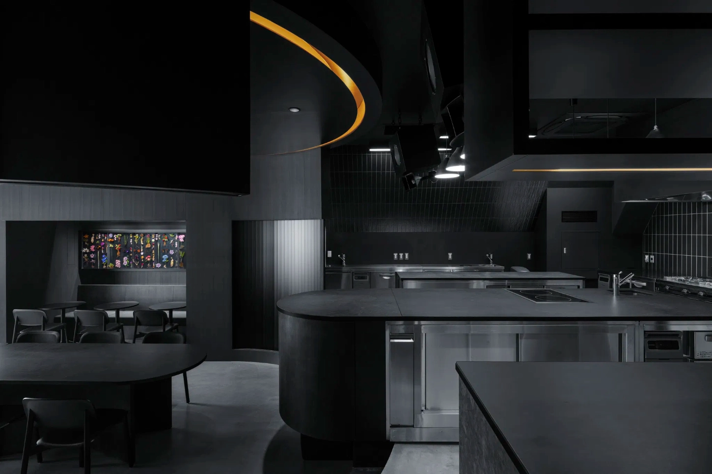 Burnside by Snøhetta — The kitchen operates as a sculptural centerpiece, its stainless steel cooking equipment arranged in bilateral symmetry around a curved central island.