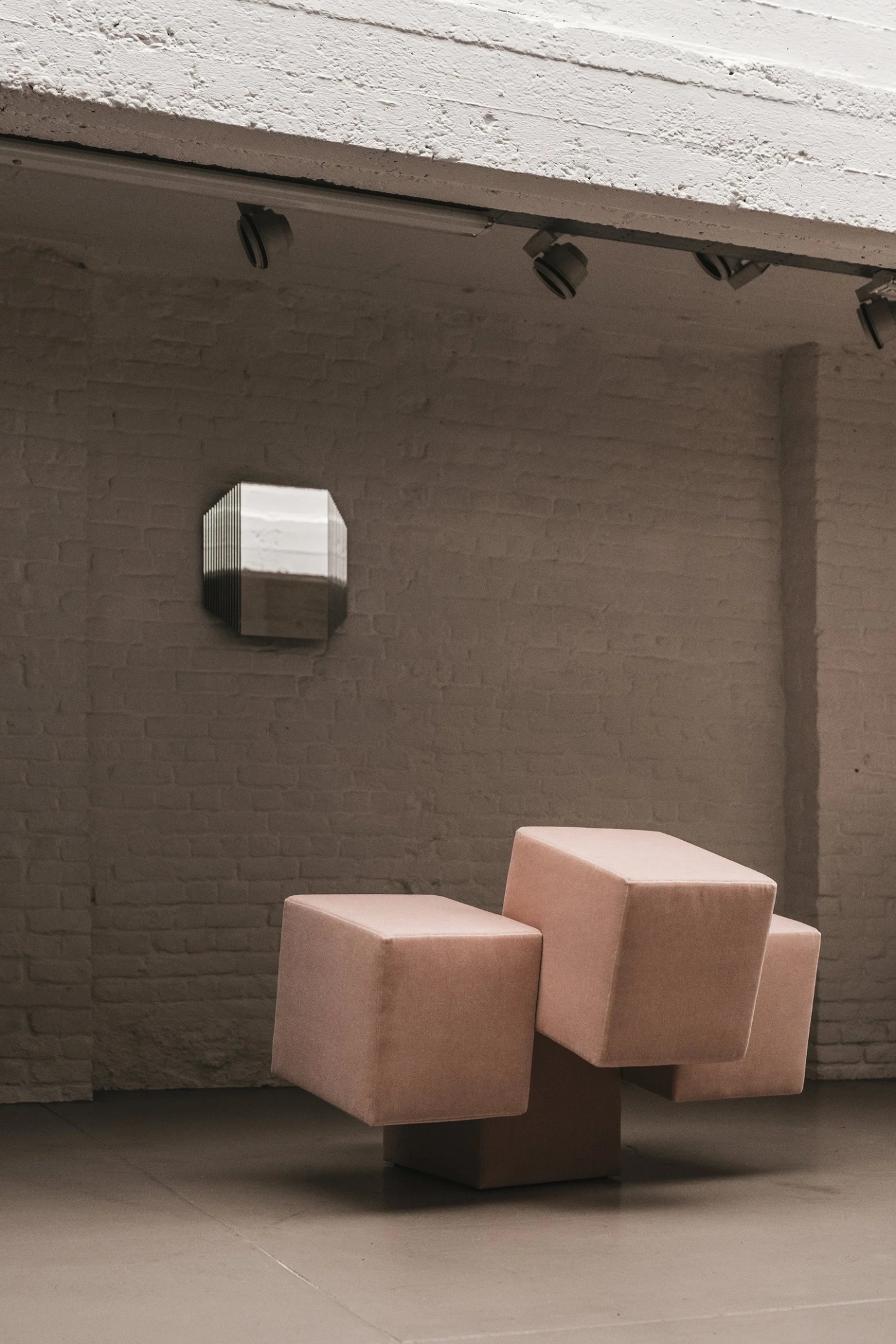 Cubist Chair by ÆTHER/MASS — Three upholstered cubic chairs in terracotta and cream occupy an industrial concrete floor, arranged in loose triangular formation rather than conventional...