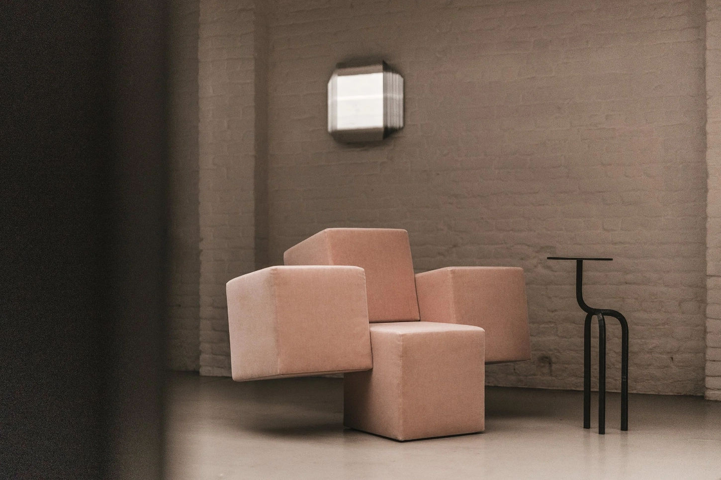 Cubist Chair by ÆTHER/MASS — Three cubic upholstered chairs with soft-edged geometric planes in terracotta and cream occupy an interior defined by charred vertical timber planks and...