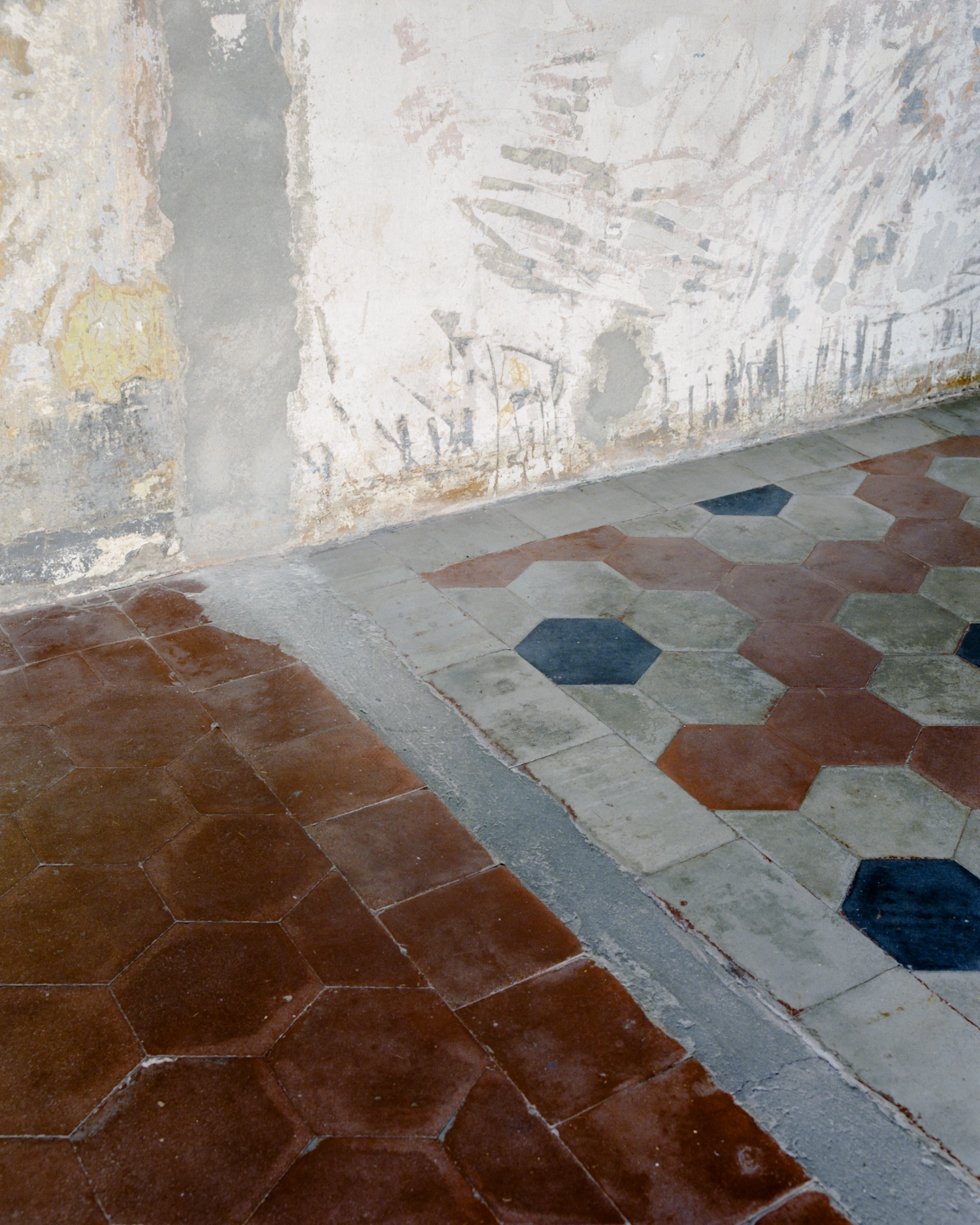 CGM Club Giovanile Milano by co.arch studio — A close-up view of the hexagonal terrazzo floor detail, revealing the layered color palette of rust-toned, cream, grey, and dark blue tiles arranged in...