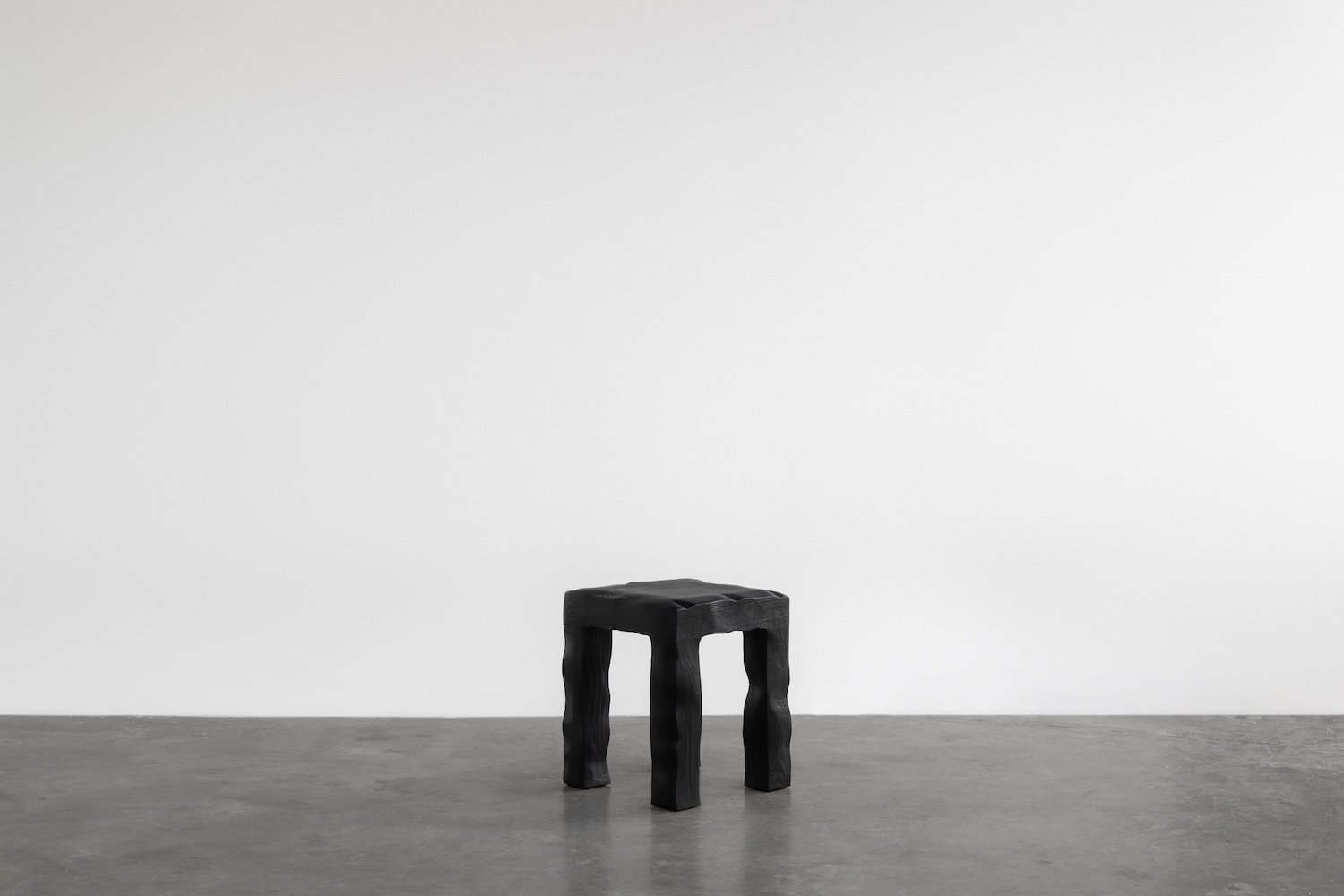 KAMEH 0.5 Collection by KAMEH — A hand-sculpted chair from the KAMEH 0.5 collection rendered in charred timber with pronounced wood grain striations.