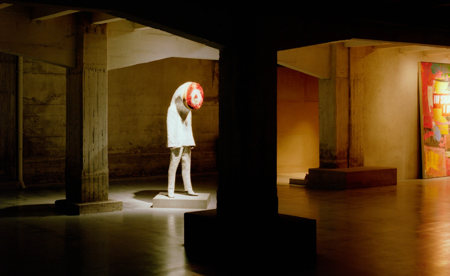 SOLO CSV Art Space by Estudio Herreros — A sculptural figure in white renders stands beneath a massive circular concrete portal, head bowed toward a red geometric form.