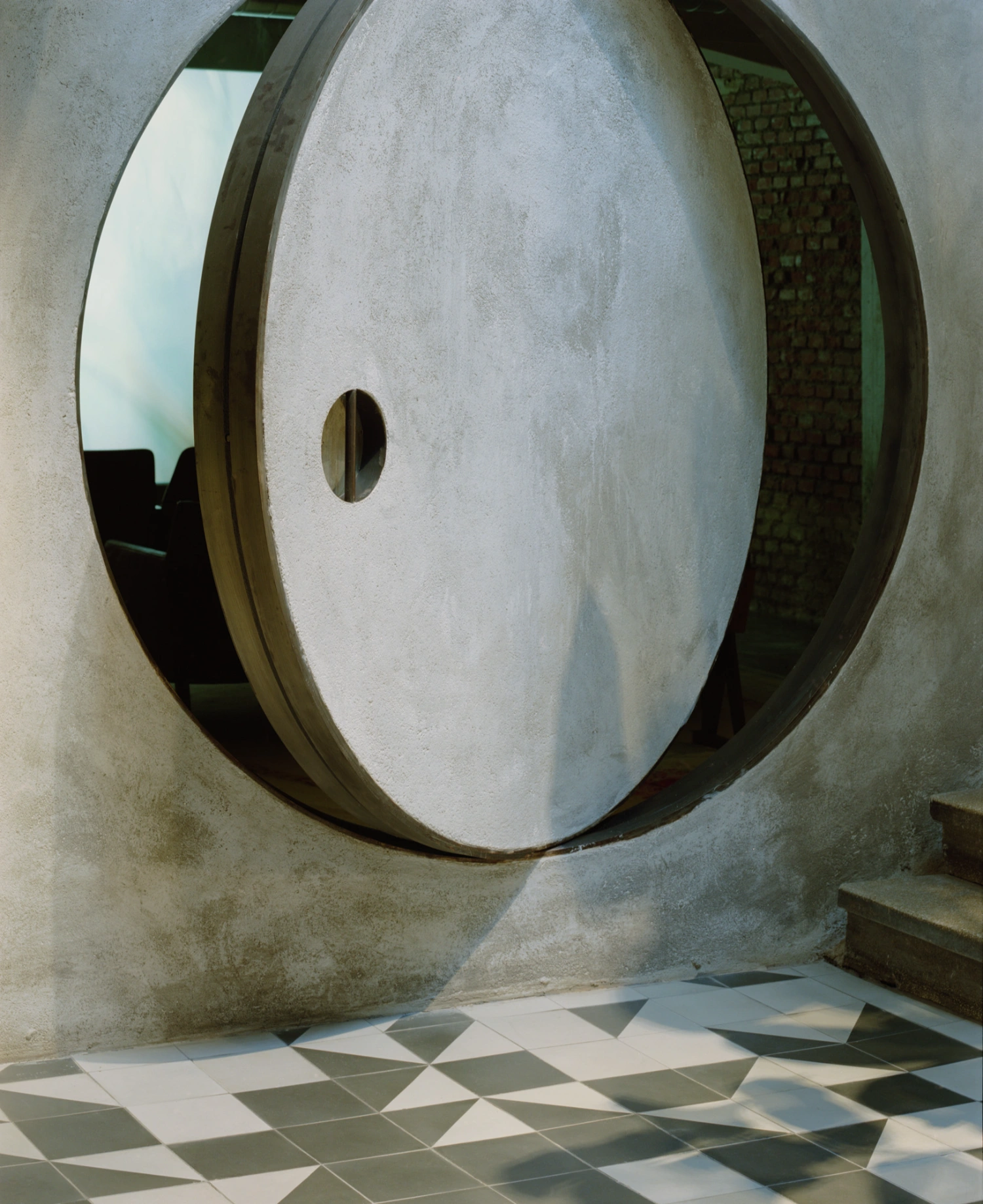 SOLO CSV Art Space by Estudio Herreros — A monolithic concrete ring dominates the interior threshold, its outer surface rendered in white plaster while exposing raw brick through side apertures.