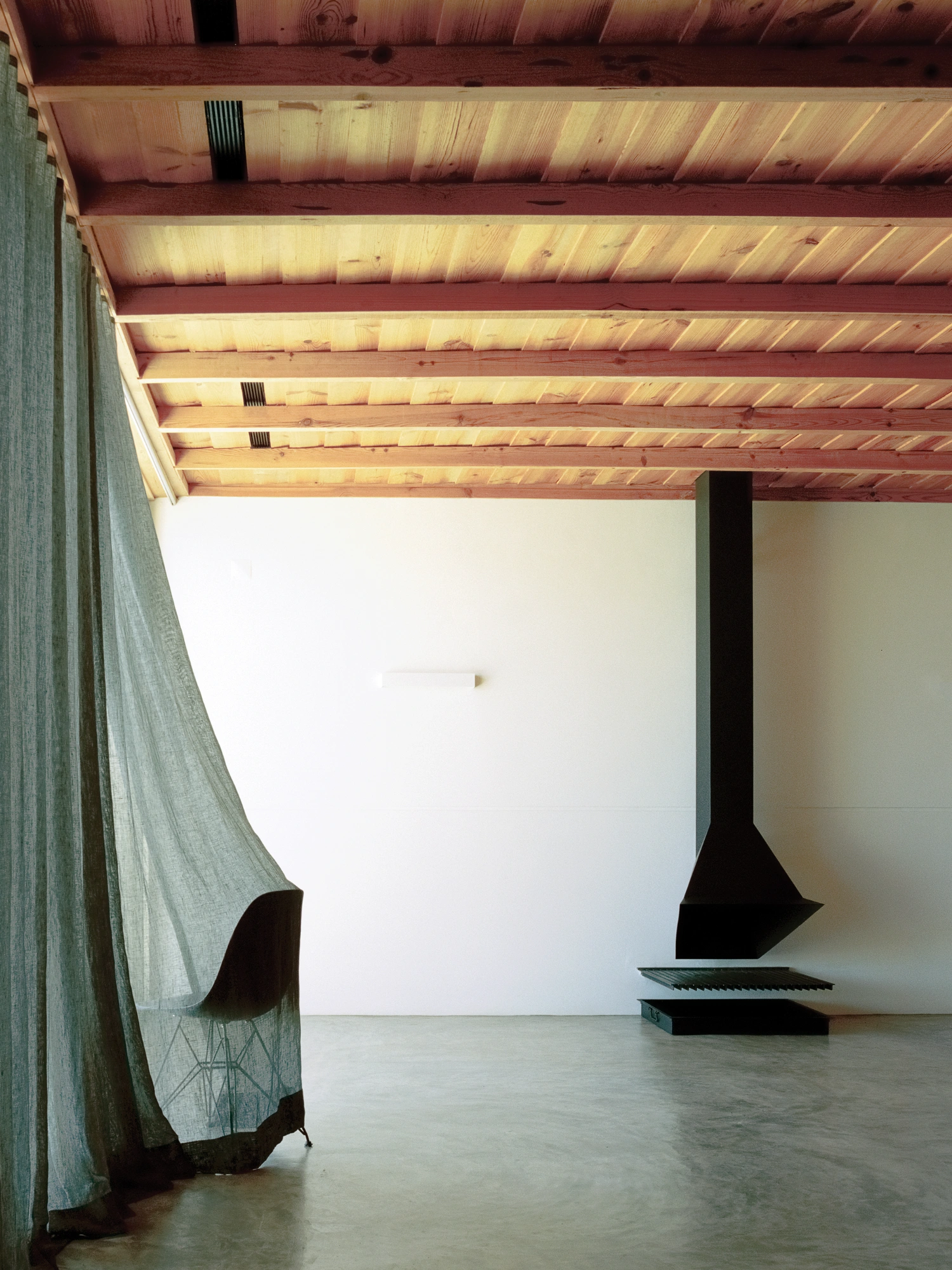 Herdade da Cardeira Winery by EMBAIXADA by EMBAIXADA arquitectura — Interior volume with exposed timber beam structure overhead, painted a warm honey tone with visible knots and grain.