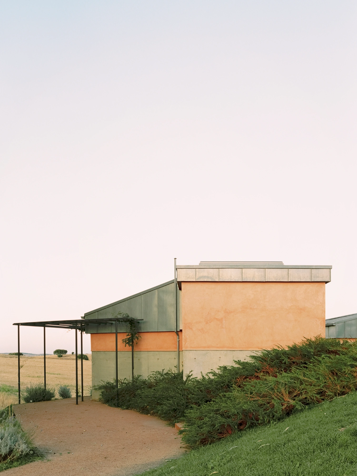 Herdade da Cardeira Winery by EMBAIXADA by EMBAIXADA arquitectura — A low-angle view of the winery's entrance pavilion reveals the deliberate material stratification across its facade.