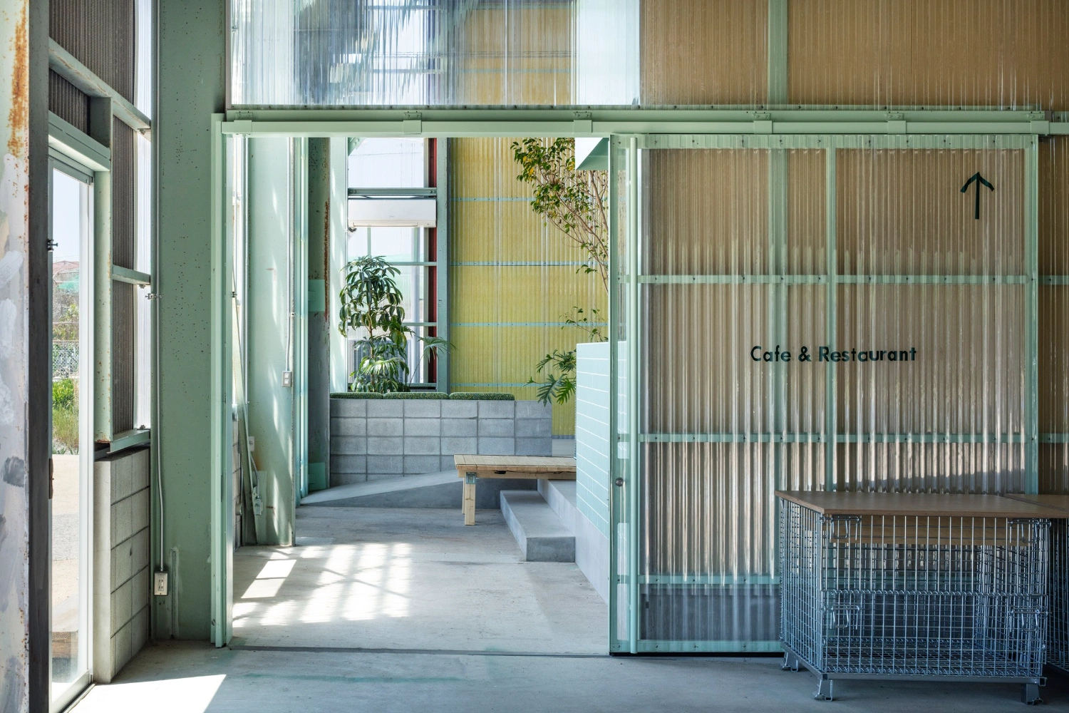 Teshima Factory Cafe by Schemata Architects — The entrance threshold frames a measured transition between exterior concrete forecourt and interior yellow-painted volume.