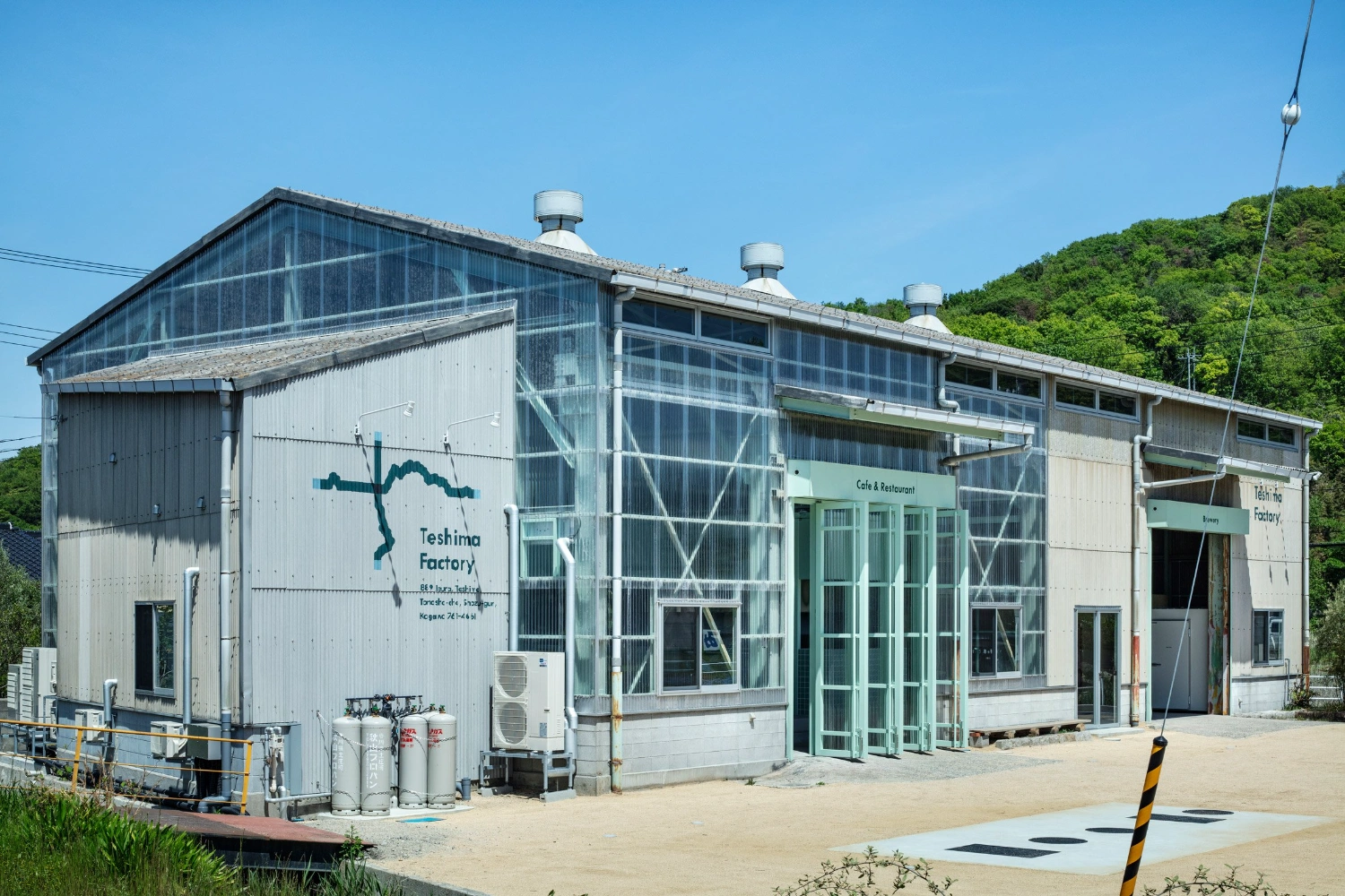 Teshima Factory Cafe by Schemata Architects — The Teshima Factory Cafe presents a bifurcated industrial envelope in full daylight.