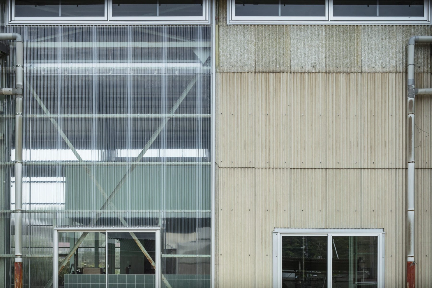 Teshima Factory Cafe by Schemata Architects — The facade demonstrates a material and structural duality: translucent corrugated polycarbonate panels dominate the left section, their vertical ribbing...