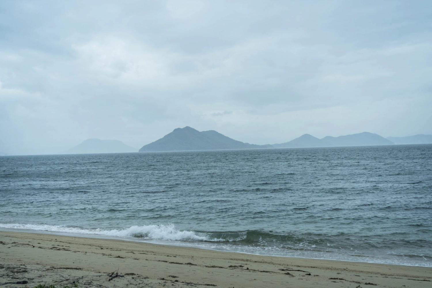 Teshima Factory Cafe by Schemata Architects — Viewed from the beach facing the Teshima Factory Cafe, volcanic islands emerge across the water in atmospheric perspective.