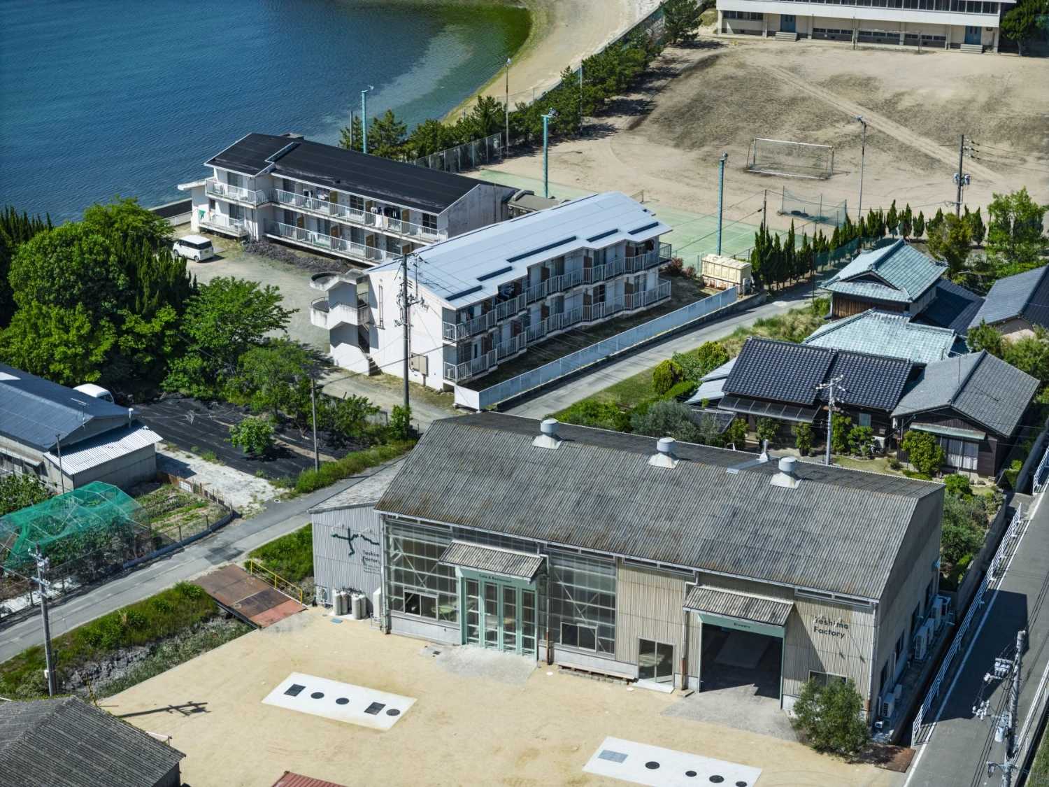 Teshima Factory Cafe by Schemata Architects — Aerial view of the Teshima Factory Cafe reveals the building's dual materiality and spatial organization.