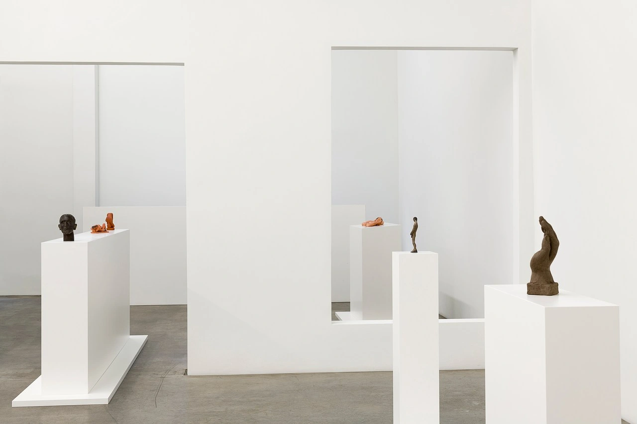 La scorza by Louis Fratino at Galerie Neu — Louis Fratino's bronze and terracotta sculptures occupy a white gallery interior, arranged across stepped white pedestals at varying heights.