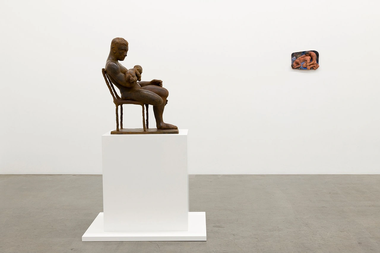 La scorza by Louis Fratino at Galerie Neu — A bronze figure seated on a wooden chair occupies the gallery's white plinth, its honey-brown patina contrasting against the institutional walls.
