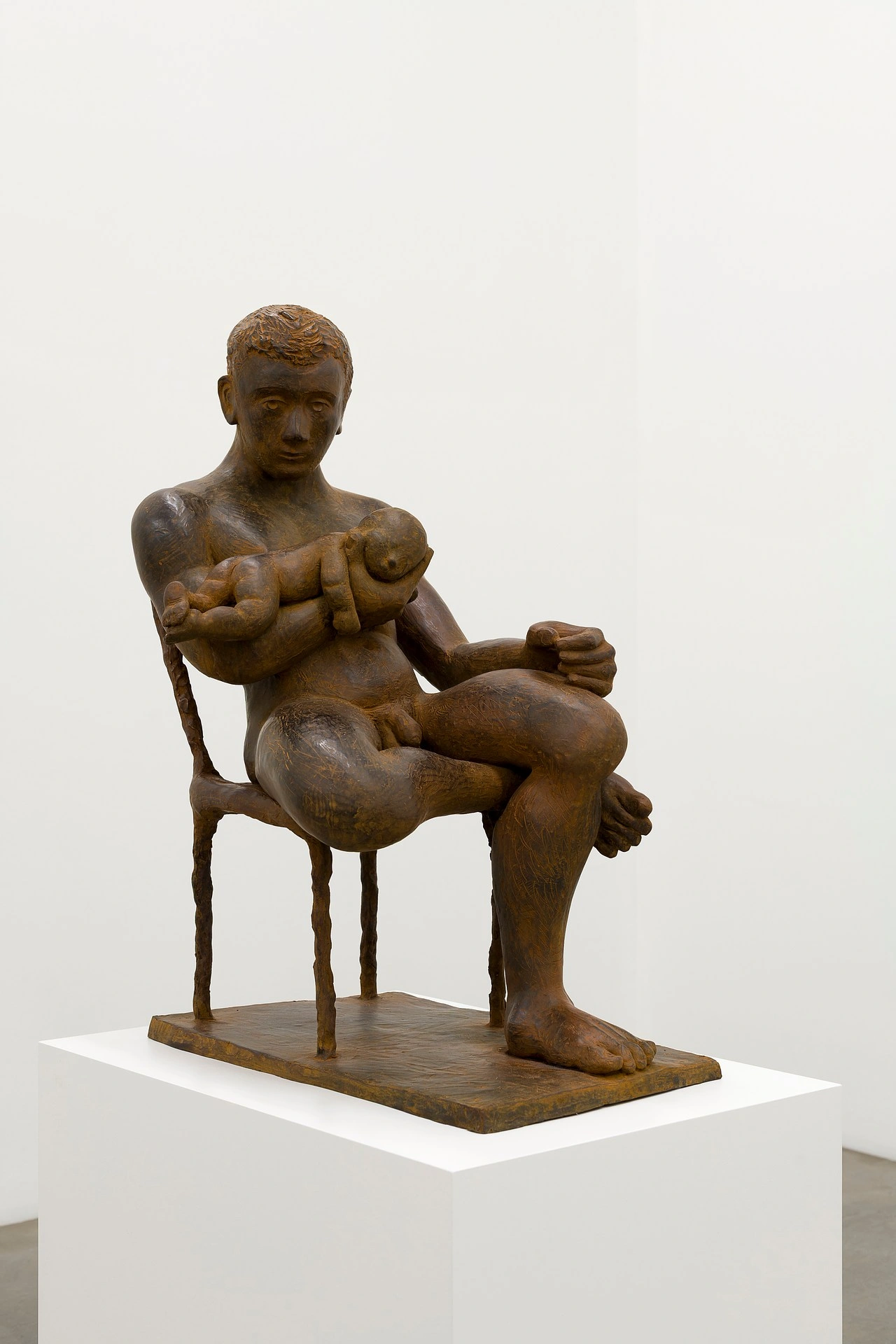 La scorza by Louis Fratino at Galerie Neu — A carved wooden figure sits cross-legged on a thin-legged wooden chair, cradling a smaller sculptural form against its torso.