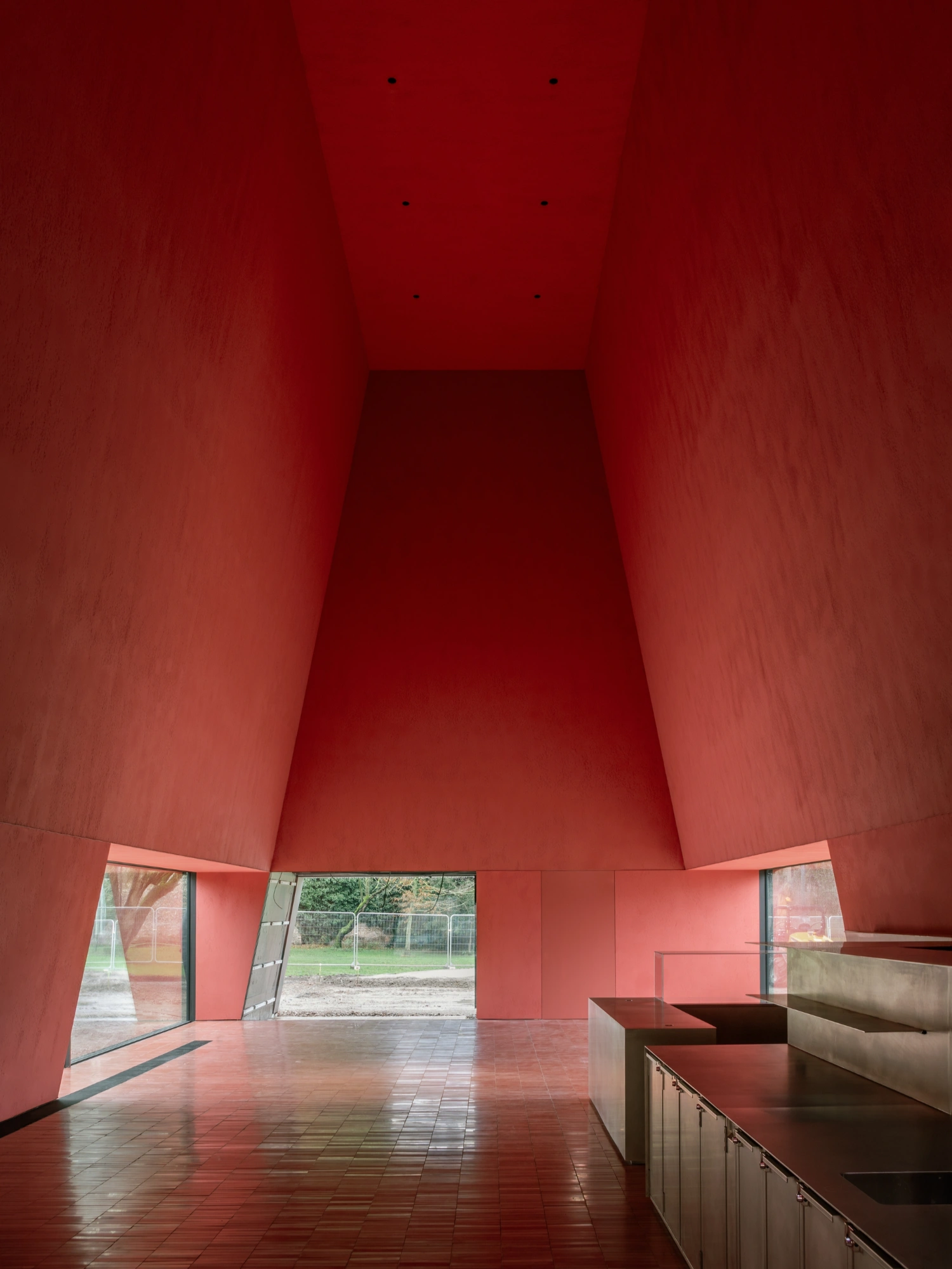 Abby Kortrijk by BAROZZI VEIGA — Interior view of the new gallery space within Abby Kortrijk, characterized by a tapered concrete volume with a dramatically sloped ceiling that narrows...