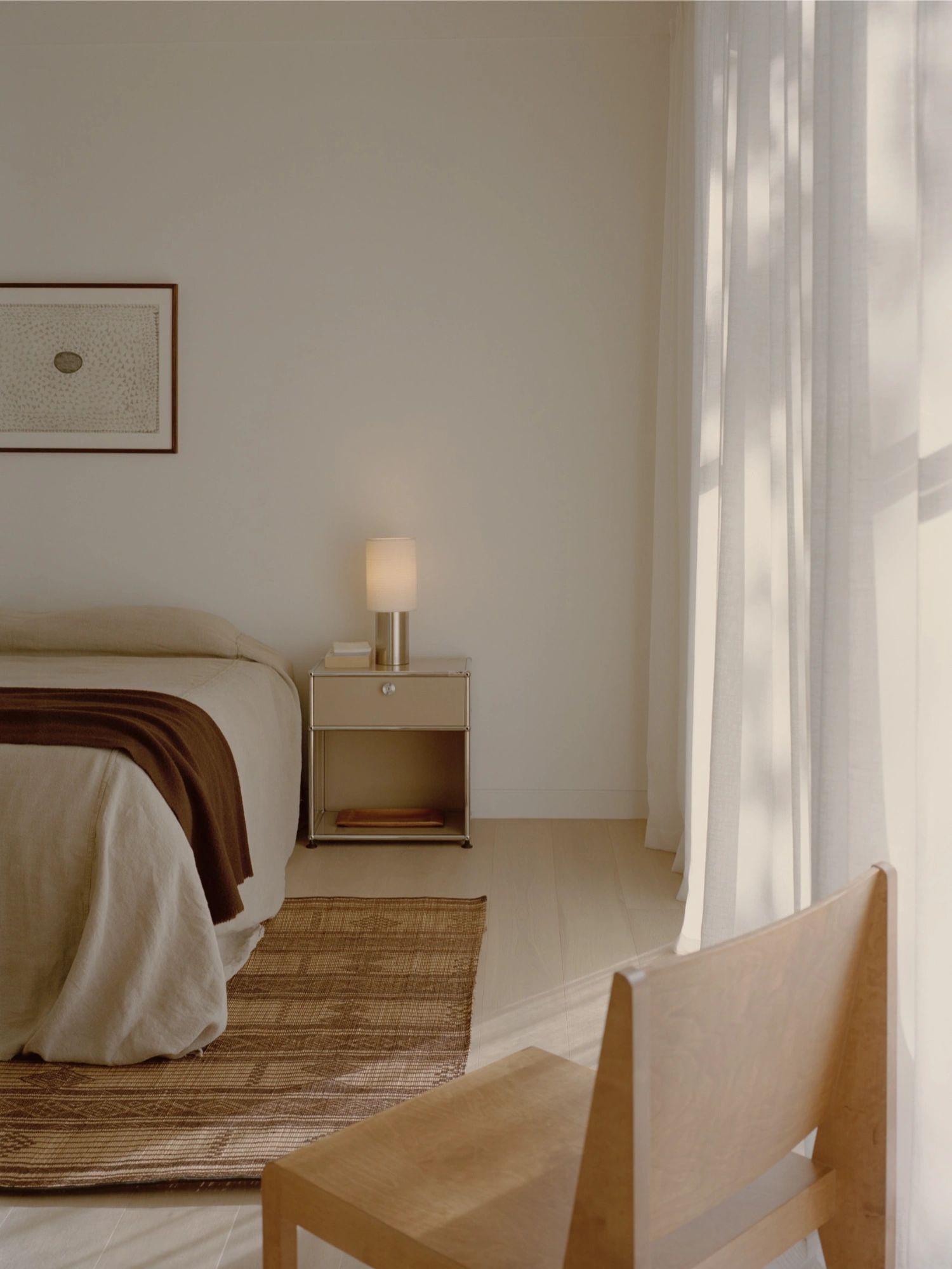 Mount Martha House by Victoria Merrett Architects — A bedroom interior viewed through a timber-framed threshold, revealing a bedside composition of restrained geometry and material contrast.