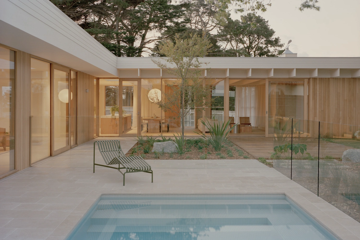 Mount Martha House by Victoria Merrett Architects — The rear courtyard reveals the residence's glazed threshold strategy: a continuous wall of timber-framed glass panels extends the full width of the facade,...