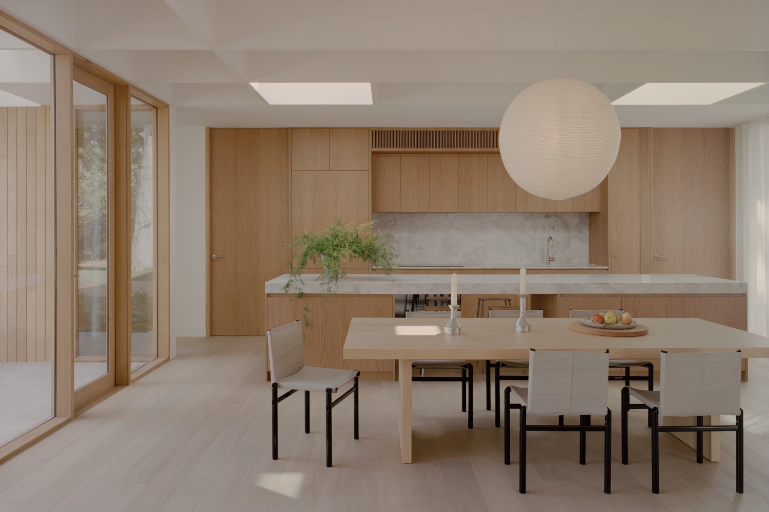 Mount Martha House by Victoria Merrett Architects — The open-plan kitchen and dining interior demonstrates a post-and-beam structural system with exposed white concrete columns supporting the flat roof plane...