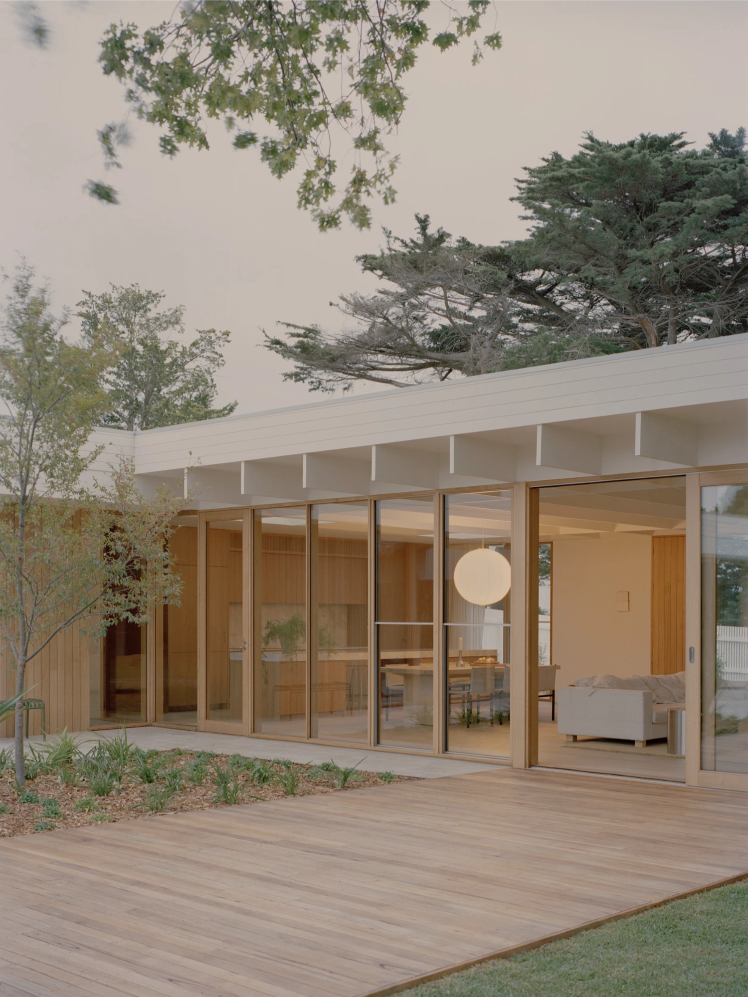 Mount Martha House by Victoria Merrett Architects — The rear facade of Mount Martha House demonstrates a systematic transparency through a continuous glazed wall system with timber-framed mullions, revealing...
