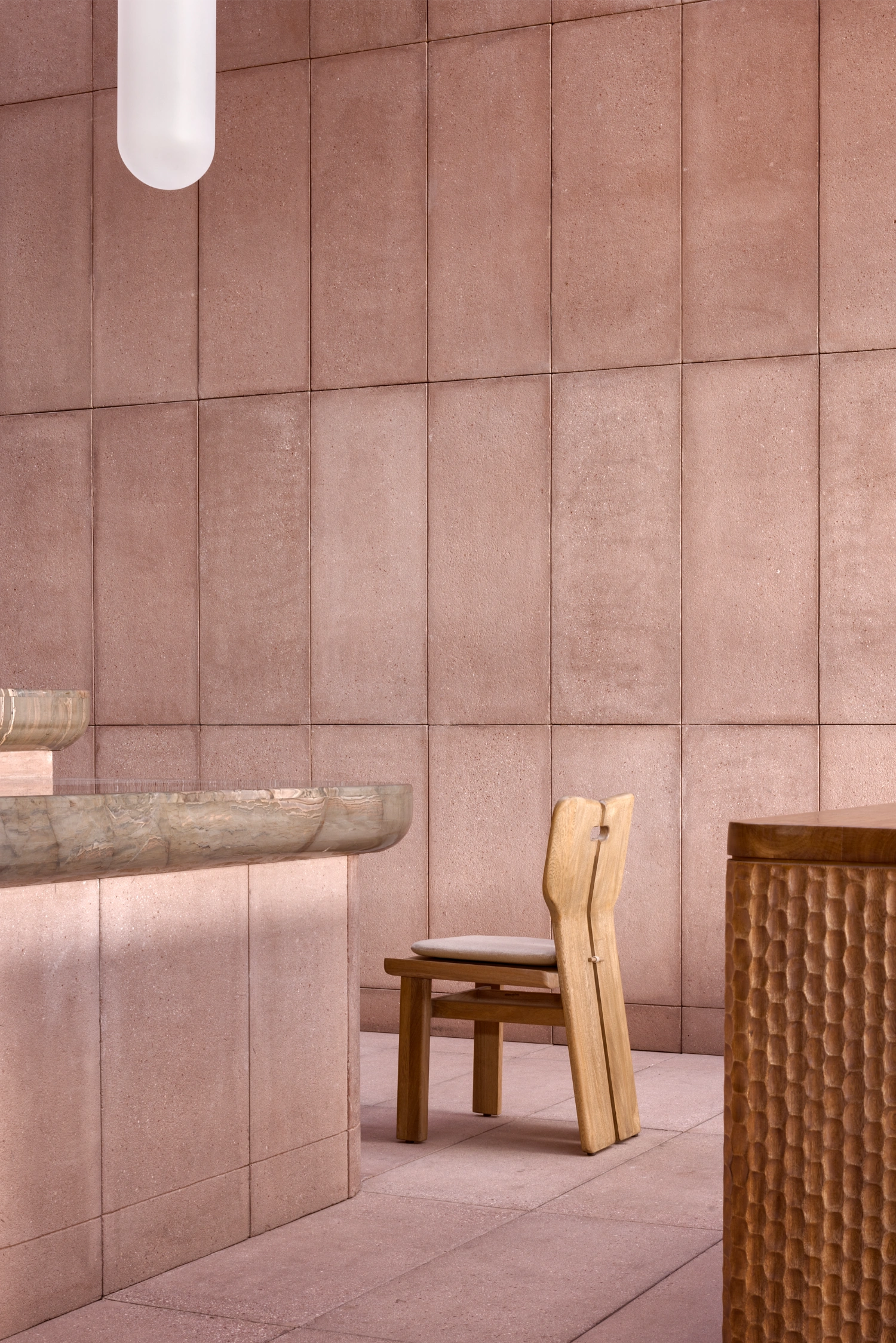 Rubra Restaurant by Ignacio Urquiza + Ana Paula de Alba — A centered composition within Rubra's mauve-pink ceramic interior reveals a wooden chair with curved backrest and cushioned seat positioned symmetrically...