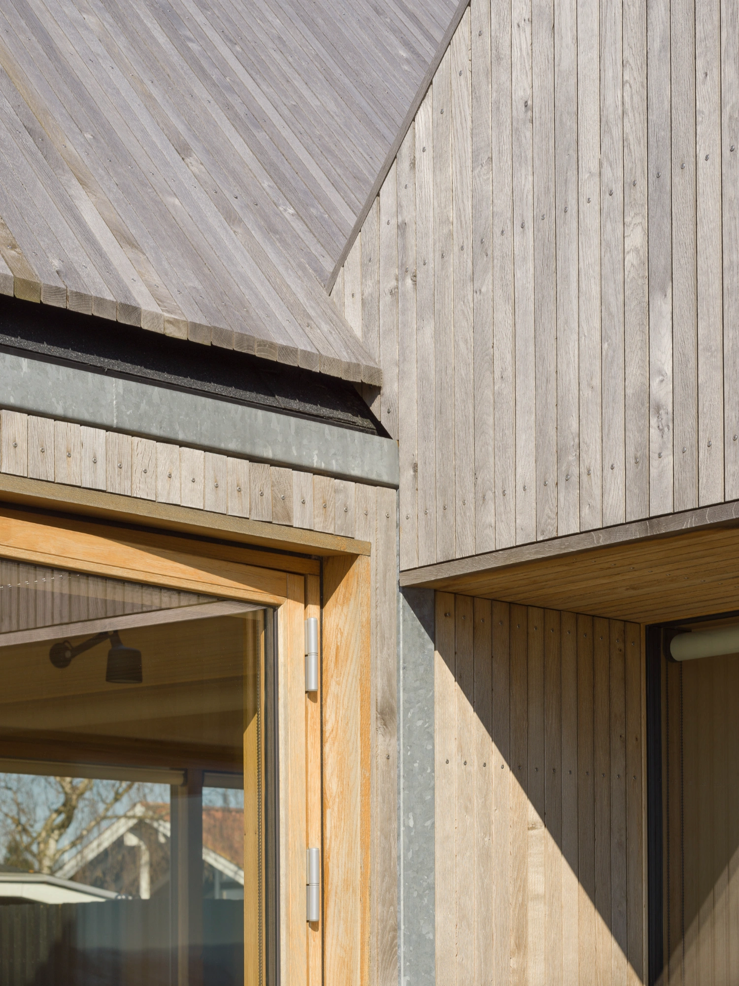 Strandvejen 35 Summer House by Jesper Kusk Arkitekter — A close-up corner detail reveals the architectural vocabulary of Strandvejen 35: vertically-aligned dark-stained oak cladding meets a pitched timber roof,...