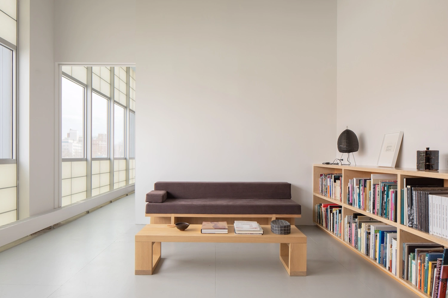 Glenn Ligon Artist’s Studio by Ravi Raj Architect — A reading room within the studio configured around a timber bench and low platform table positioned perpendicular to the gridded window wall.